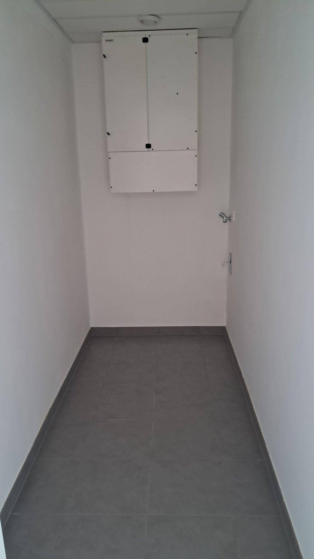 Praktischer Hauswirtschaftsraum mit grauem Fliesenboden und Elektroverteiler an der Wand.