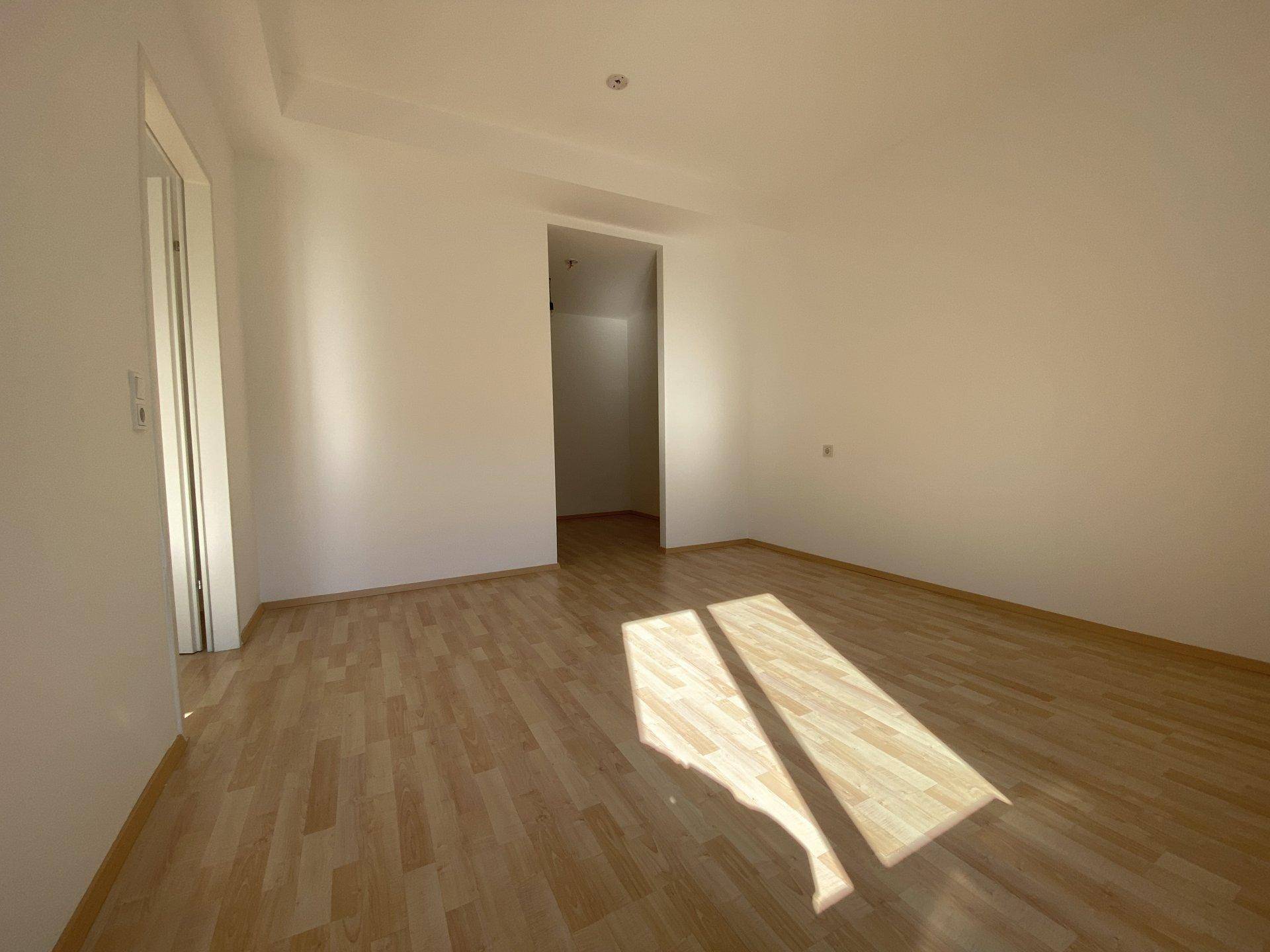 Geräumiges Zimmer mit Laminatboden und einem offenen Bereich, ideal als Ankleide oder Arbeitsplatz.