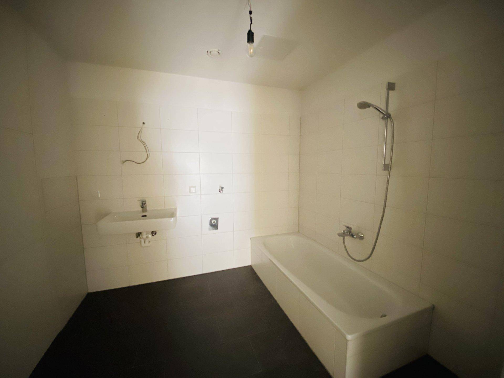 Modernes Badezimmer mit Badewanne, Waschbecken und weißen Fliesen.