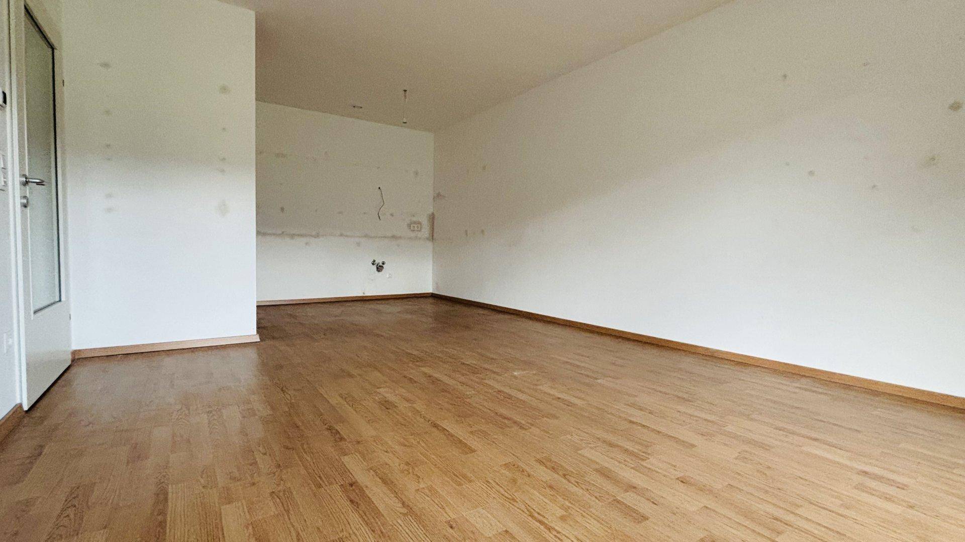 Leerer Raum mit Holzboden und weißen Wänden, bereit für individuelle Gestaltung.
