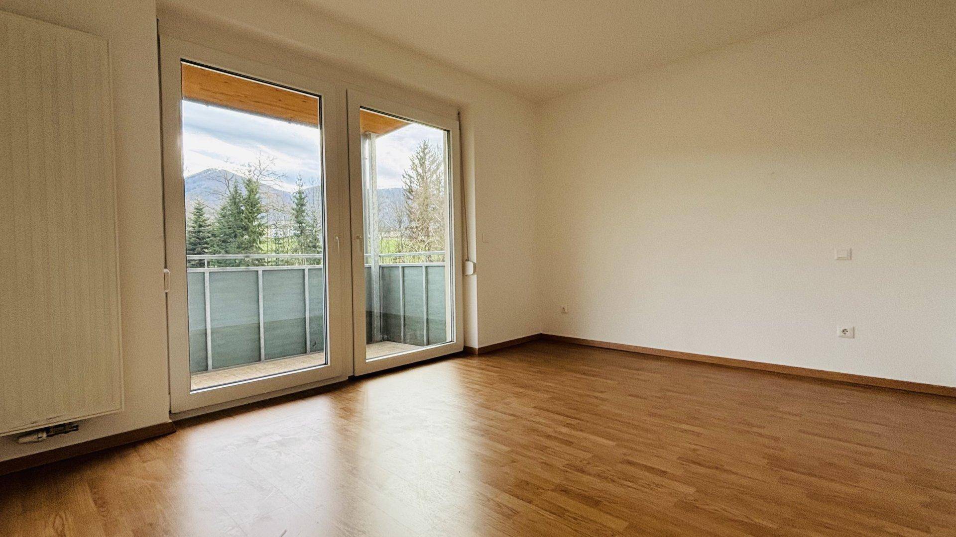 Helles Zimmer mit Holzboden und Zugang zu einem Balkon, bietet einen weiten Bergblick.