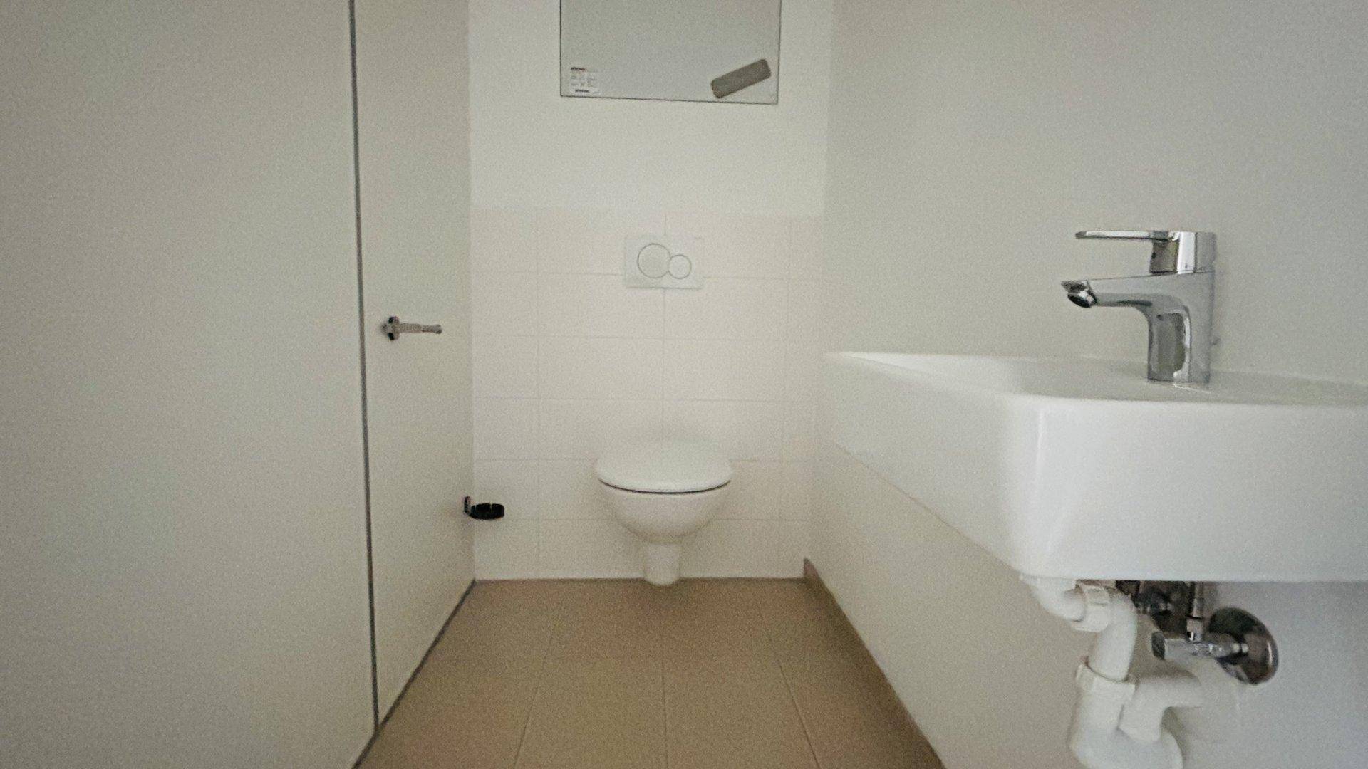 Modernes Gäste-WC mit wandhängender Toilette und kleinem Waschbecken.