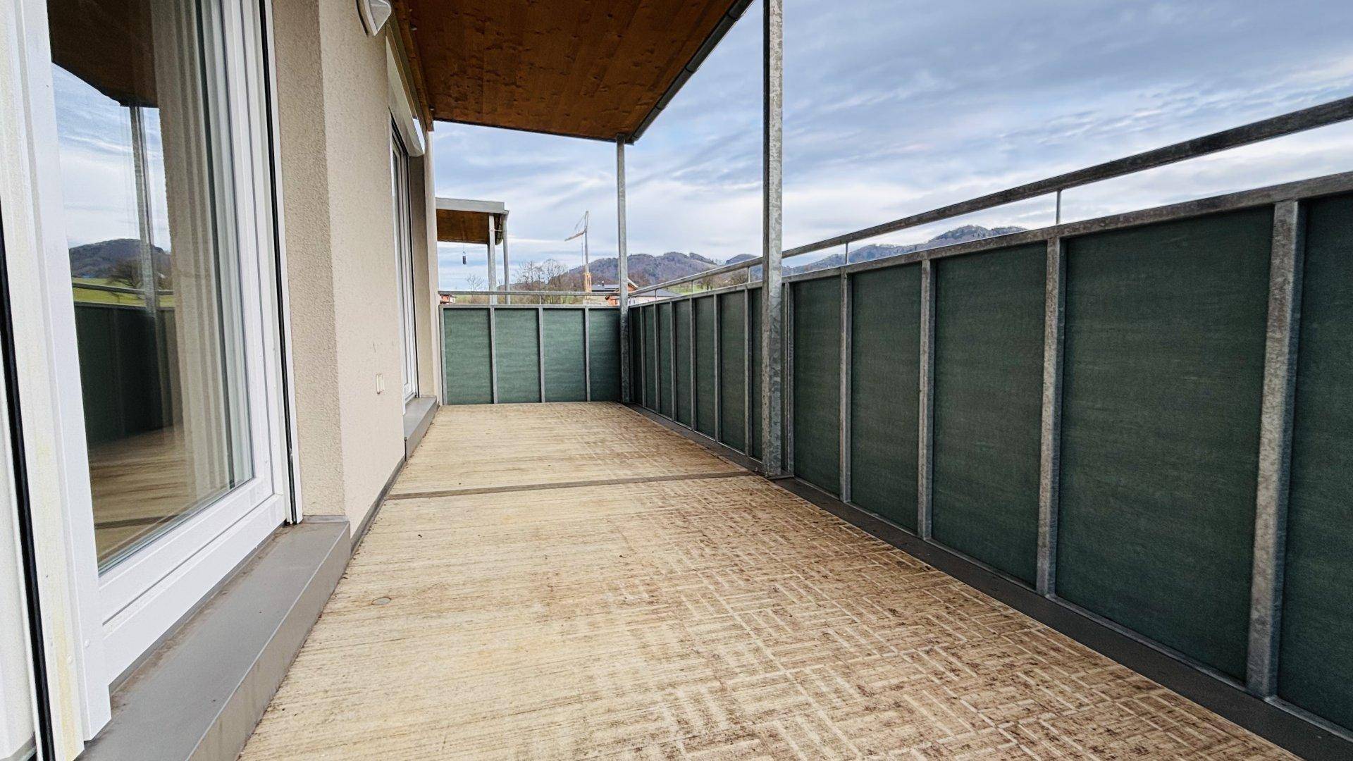Großer überdachter Balkon mit Holzdach und Blick auf die umliegende Landschaft.