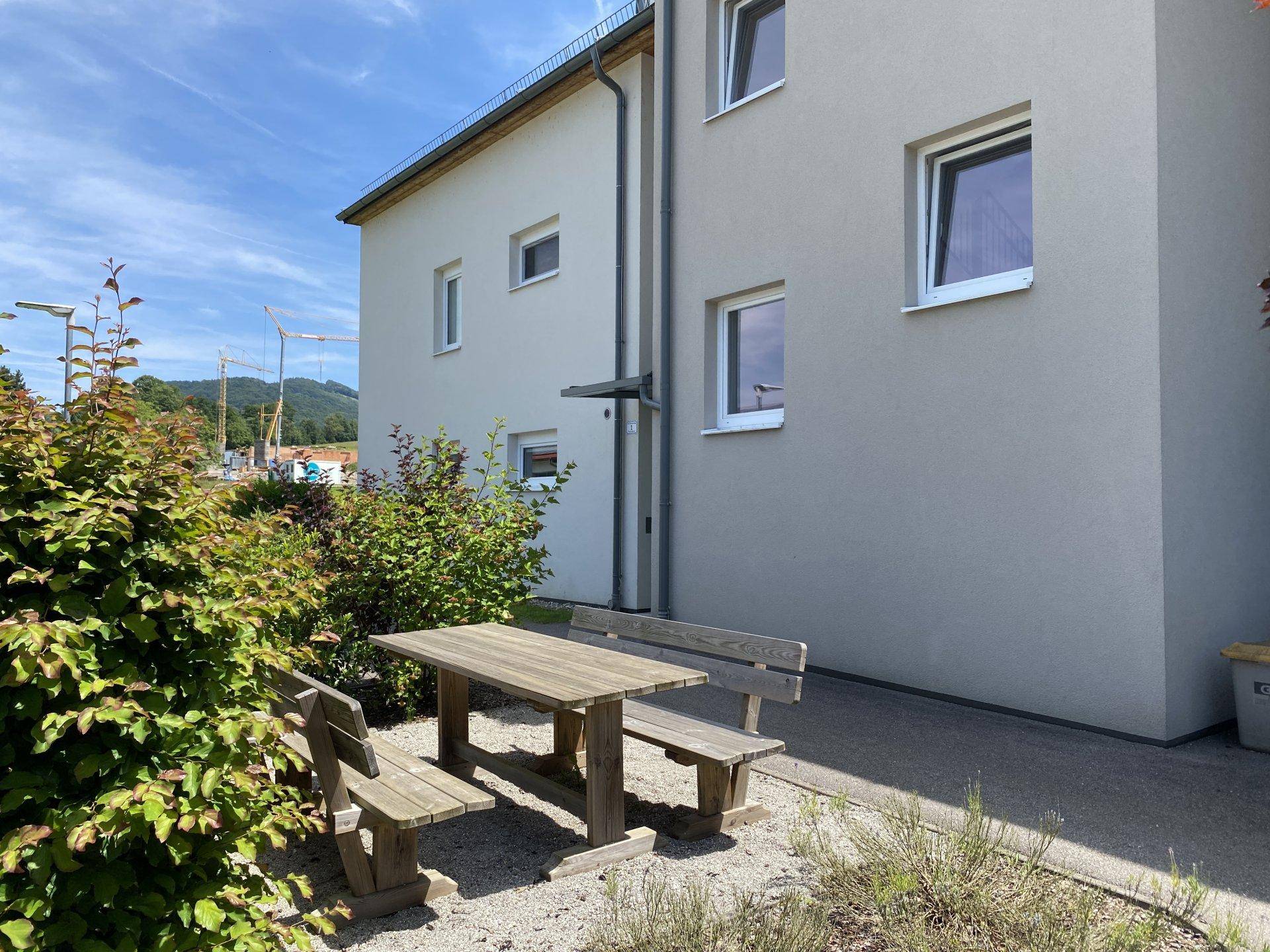 Gemütlicher Außenbereich mit Holztisch und Bänken, ideal für entspannte Stunden im Freien.