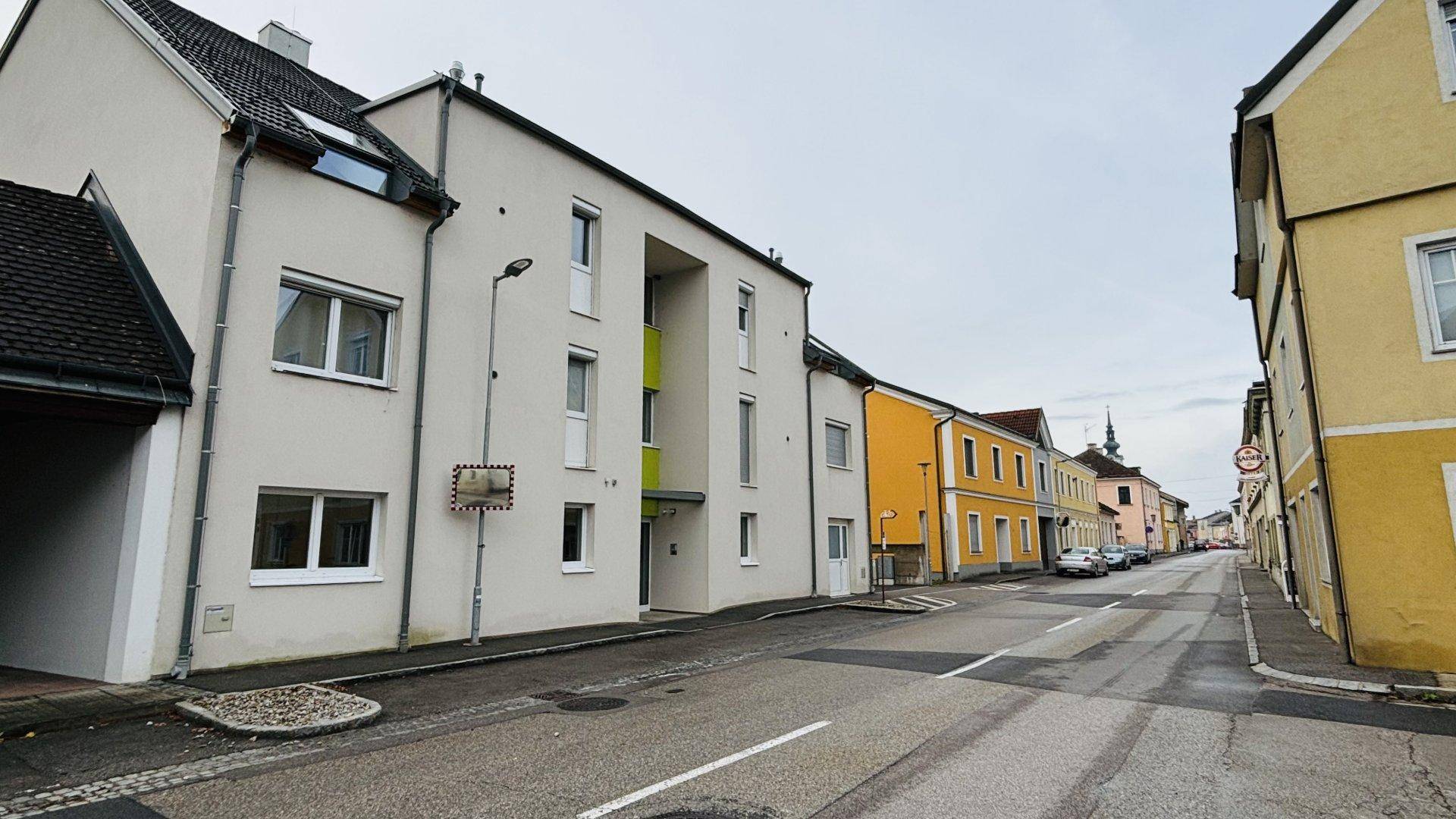 Ansicht des modernen Mehrfamilienhauses von der Straße mit angrenzenden älteren Gebäuden.