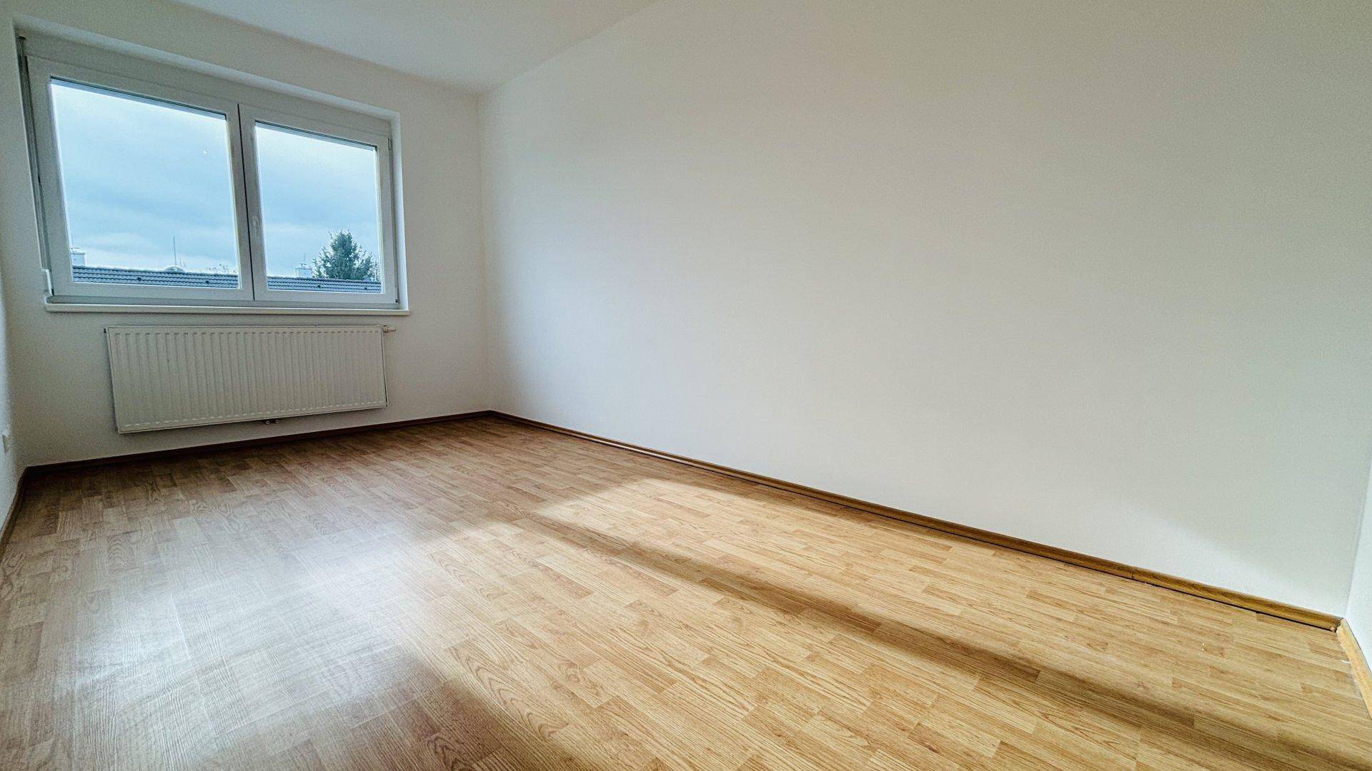 Helles Schlafzimmer mit Laminatboden und weiß gestrichenen Wänden, bereit zur Einrichtung.
