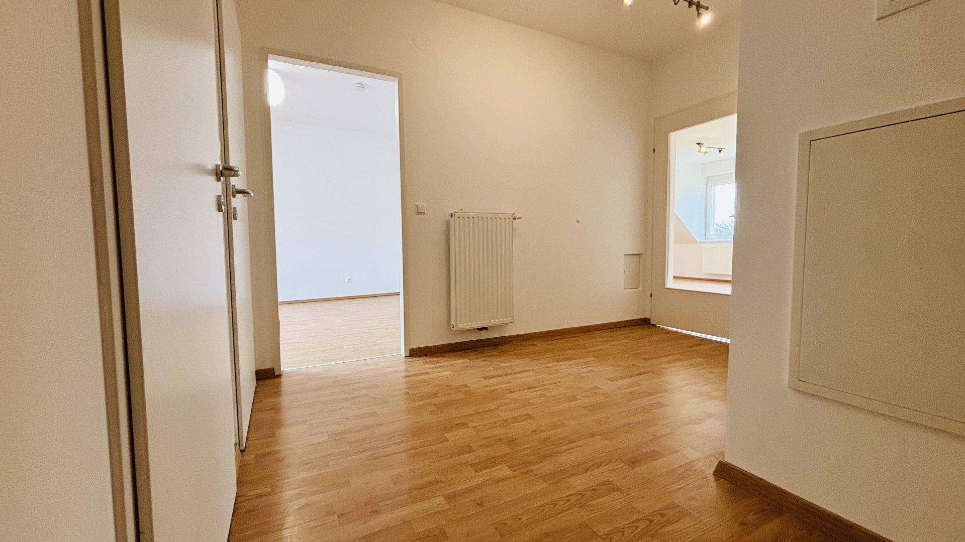 Heller Flur mit Laminatboden und Zugang zu verschiedenen Räumen der Wohnung.