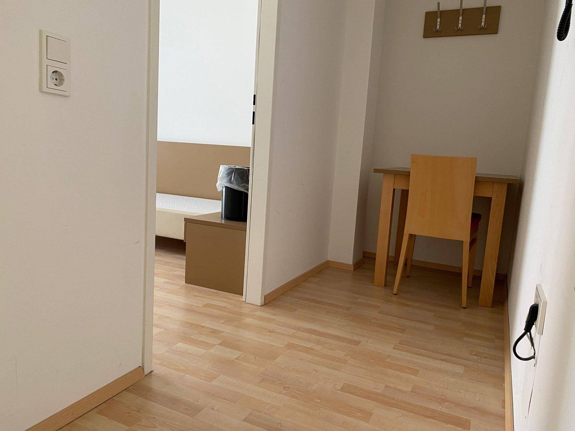 Heller Flurbereich mit Laminatboden und einem kleinen Esstisch, der zu einem weiteren Zimmer führt.