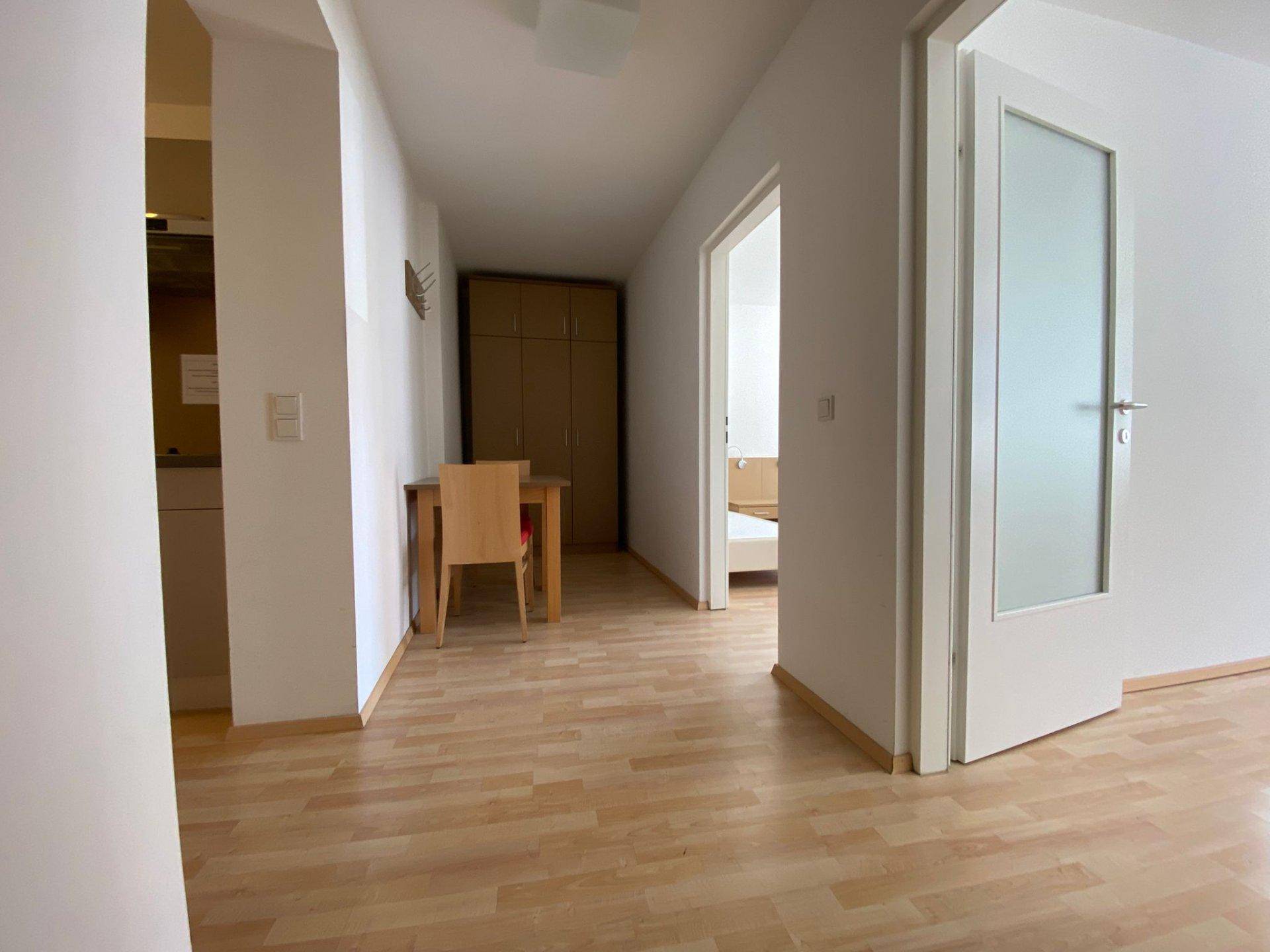 Flur mit Essbereich, Laminatboden und einem Kleiderschrank, der zu einem Schlafzimmer führt.