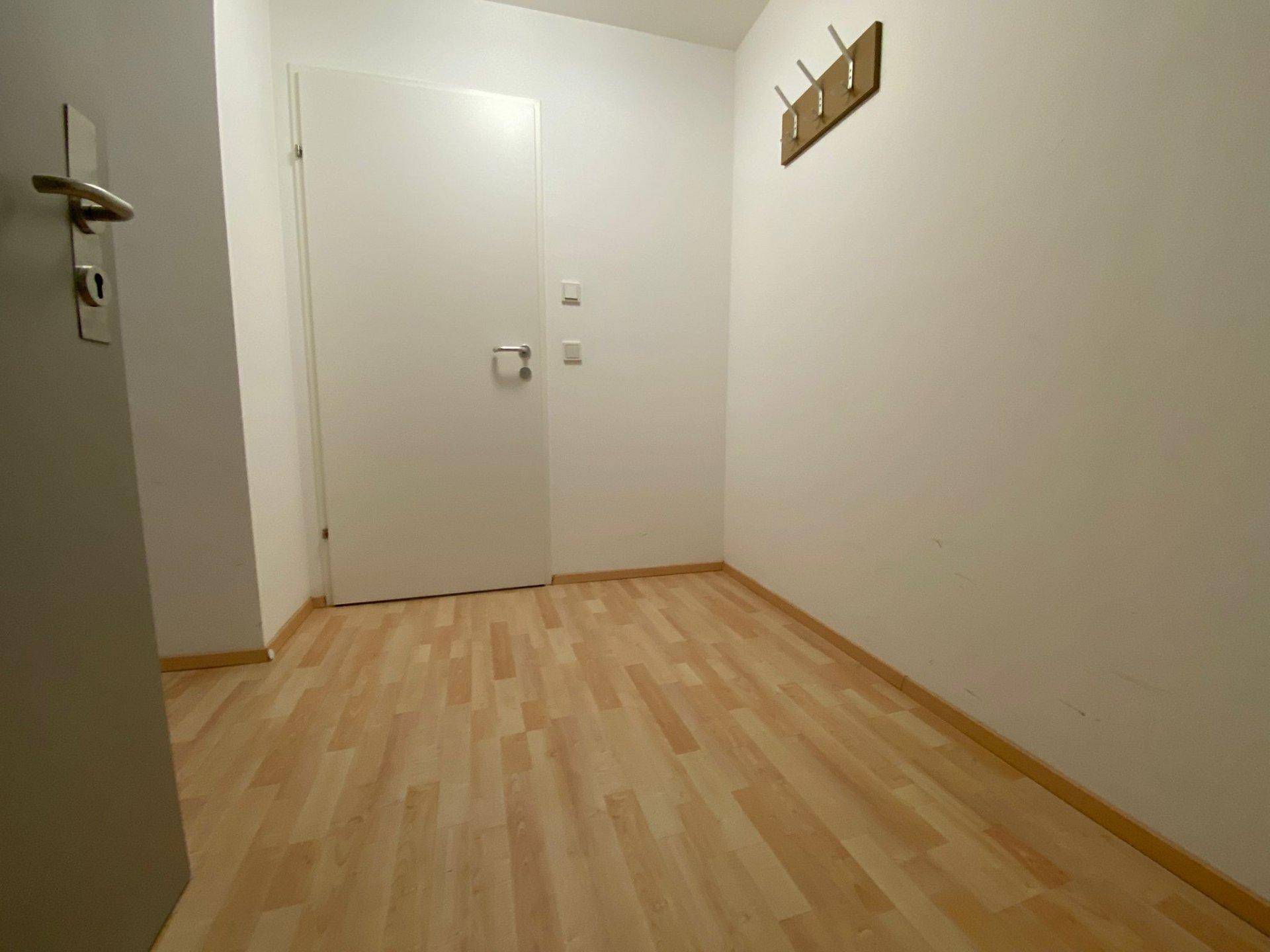 Heller Flur mit Laminatboden und einer Garderobe an der weißen Wand.