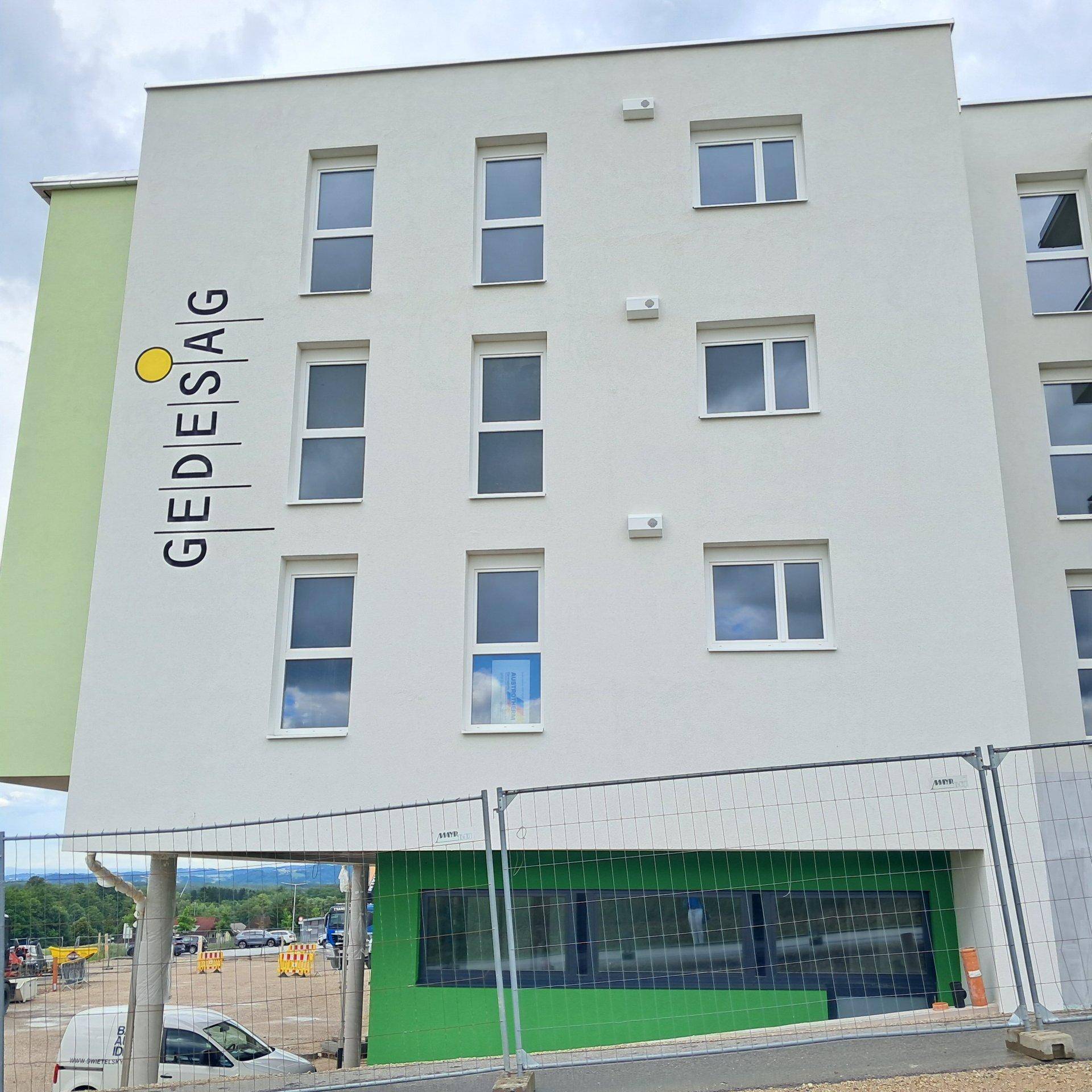 Detailansicht der modernen Gebäudefassade mit weißen Wänden und grünen Akzenten.