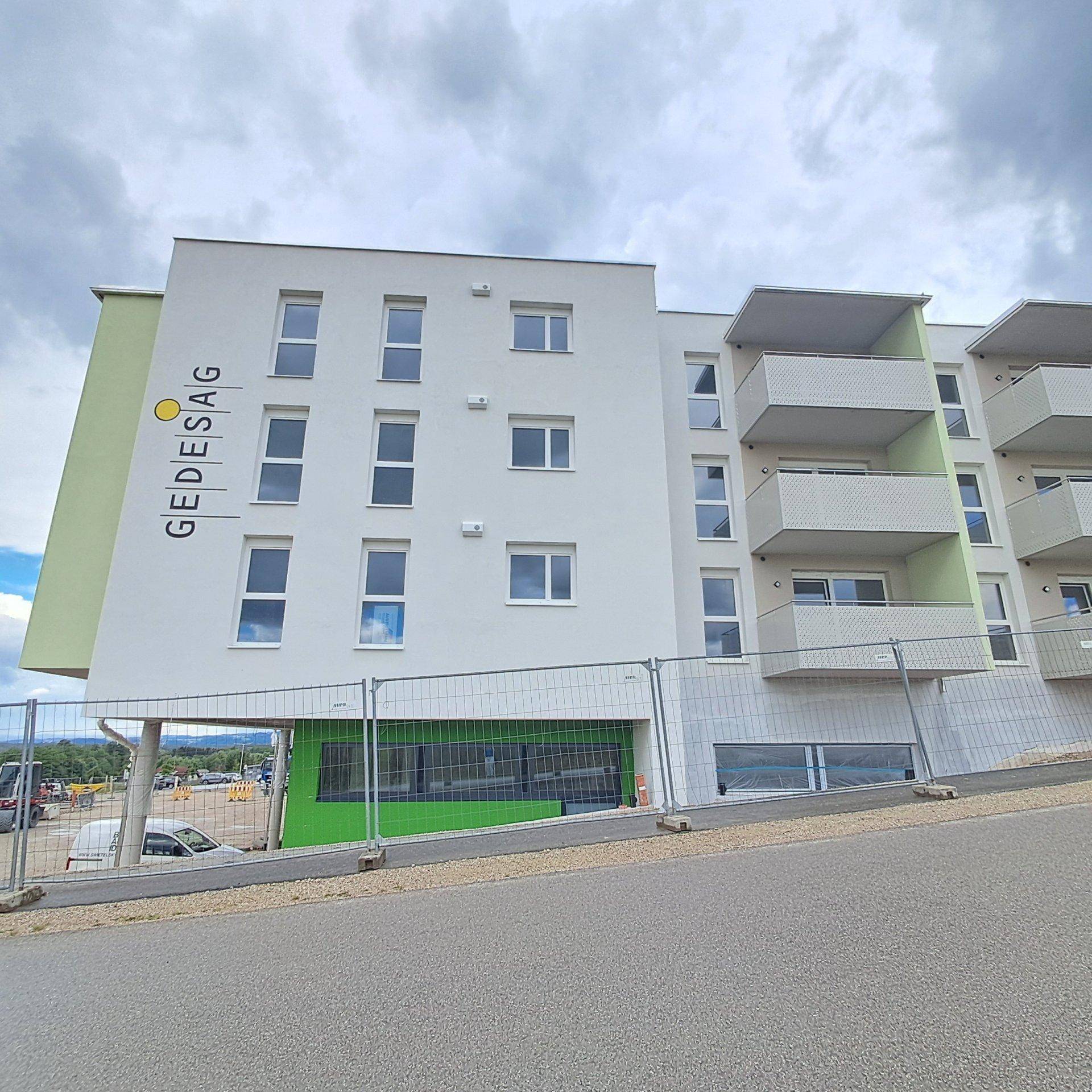 Neubau eines Mehrfamilienhauses mit moderner Architektur, Balkonen und grünen Fassadenteilen.