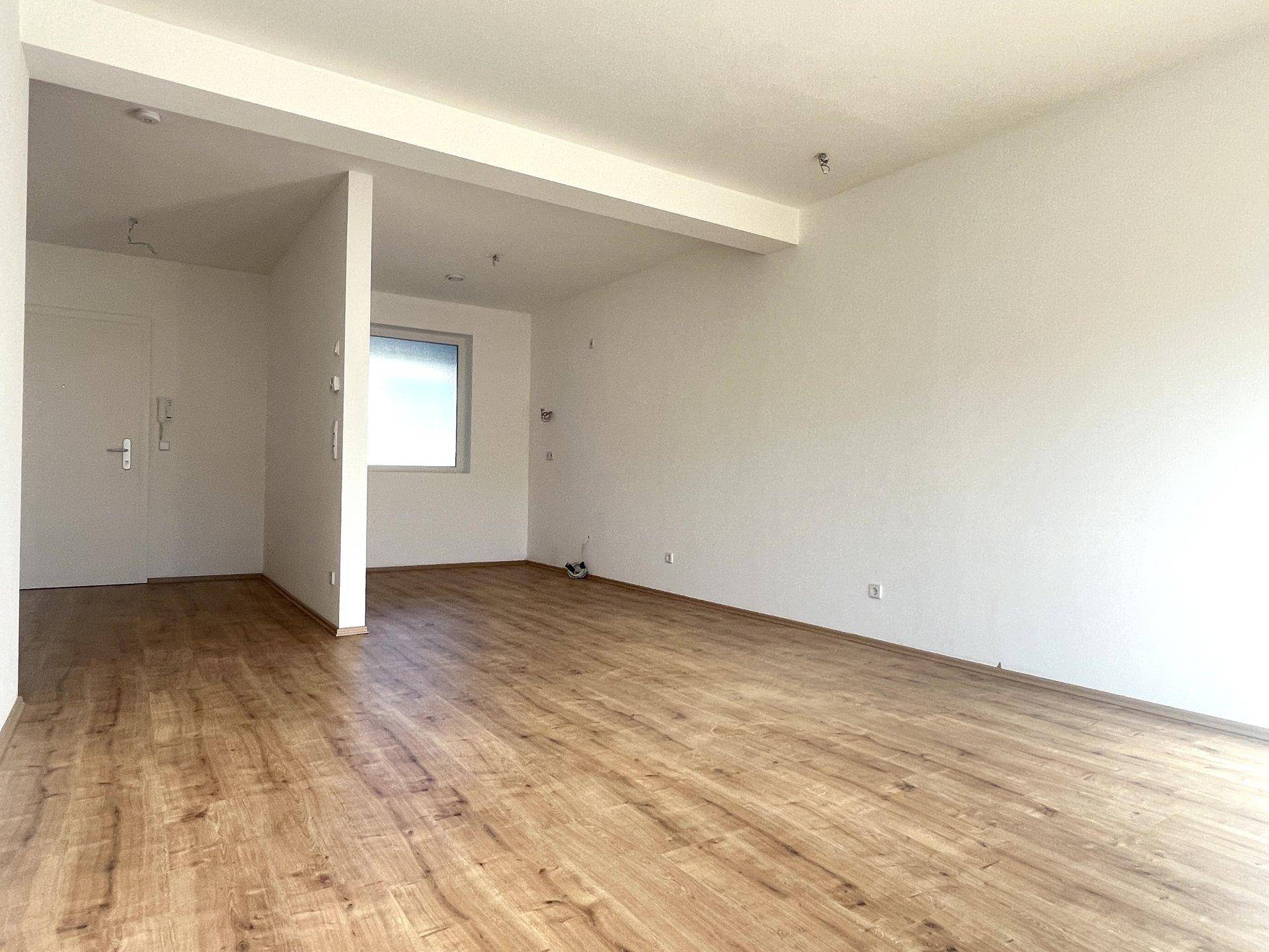 Geräumiges Wohnzimmer mit Holzboden und weiß gestrichenen Wänden, bereit für individuelle Gestaltung.