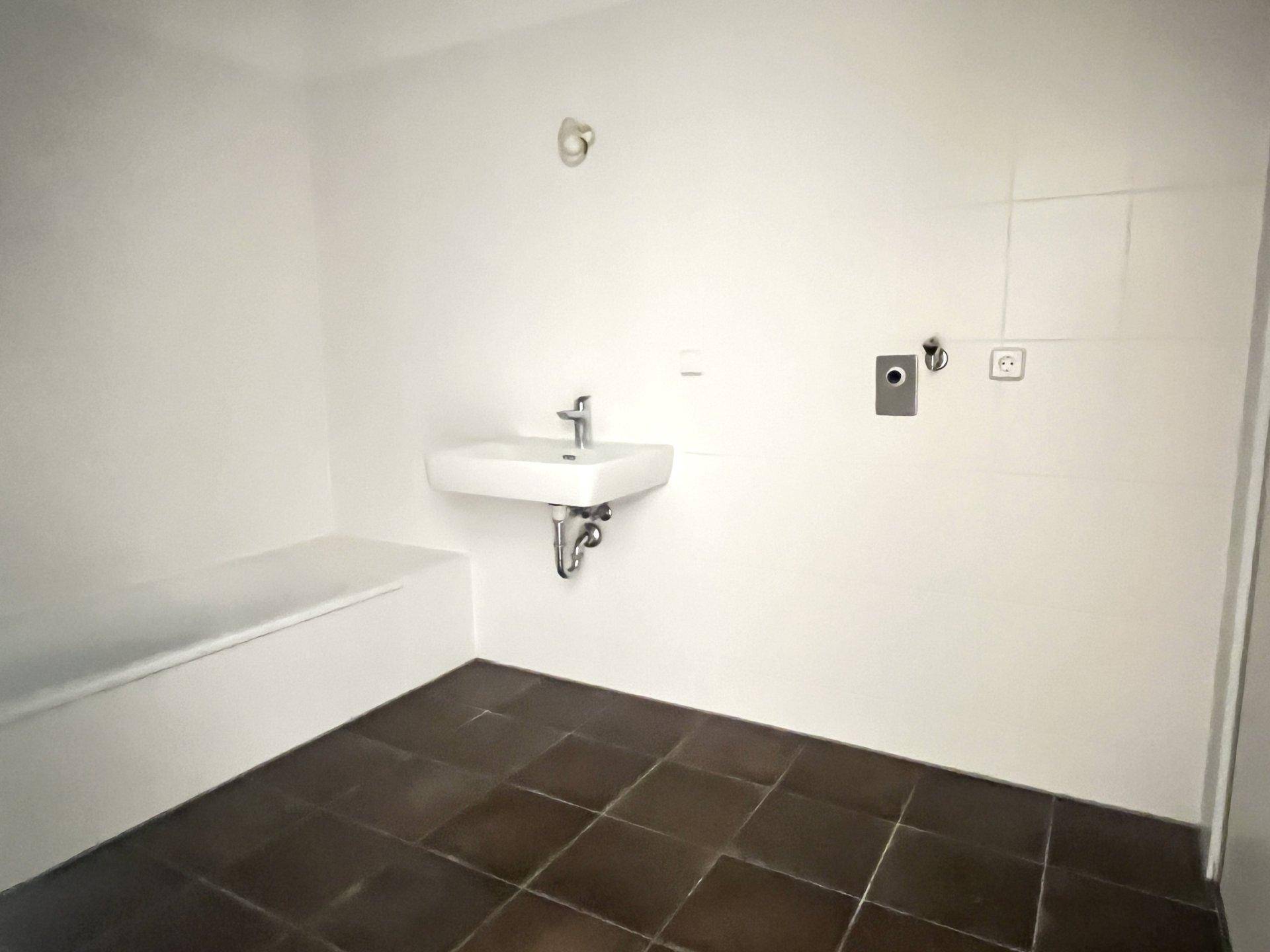 Praktischer Hauswirtschaftsraum mit Waschbecken und dunklen Fliesen, ideal für Wäsche und Lagerung.