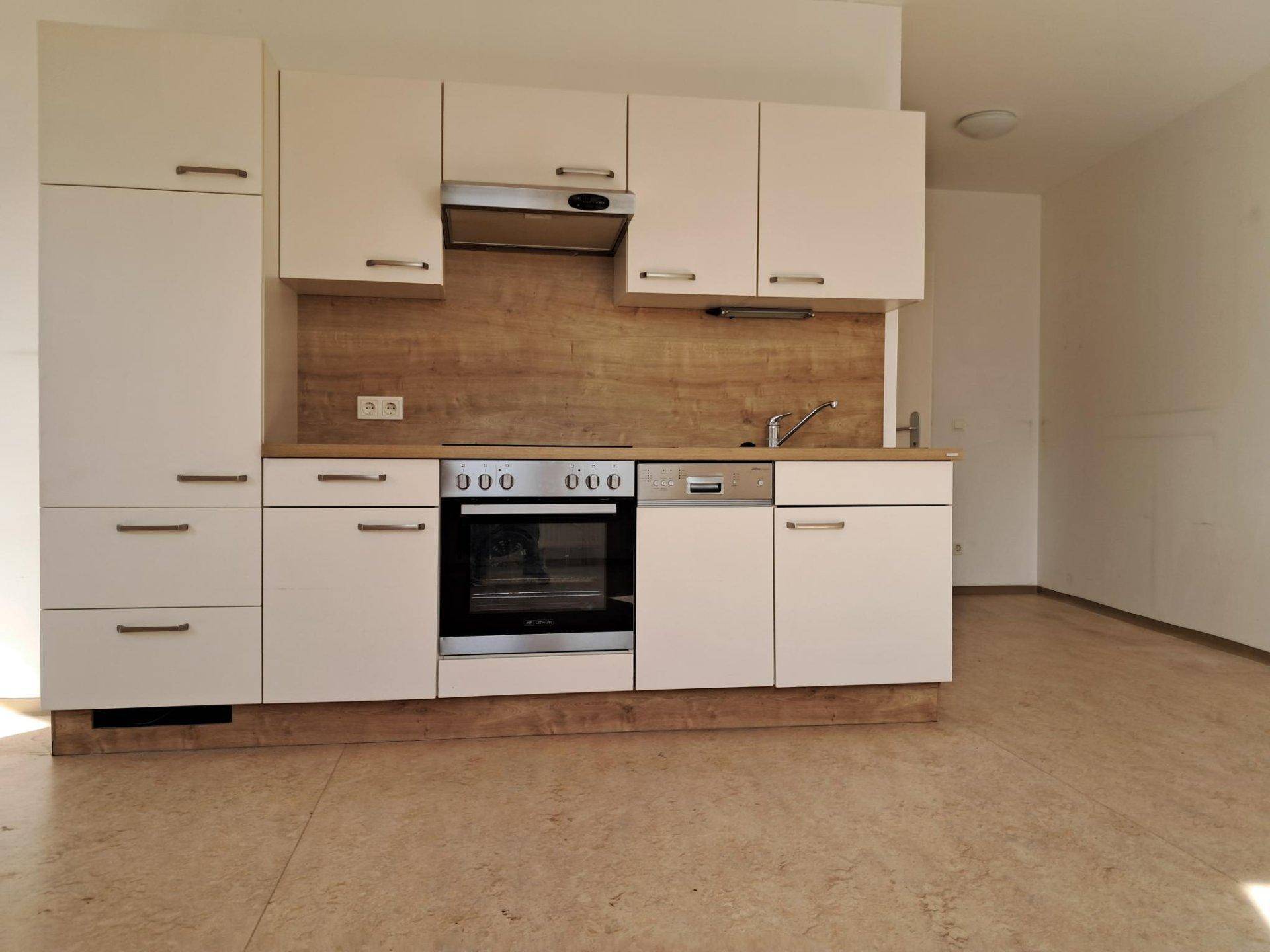 Moderne Einbauküche mit weißen Schränken, Holzoptik-Arbeitsplatte und integrierten Geräten.
