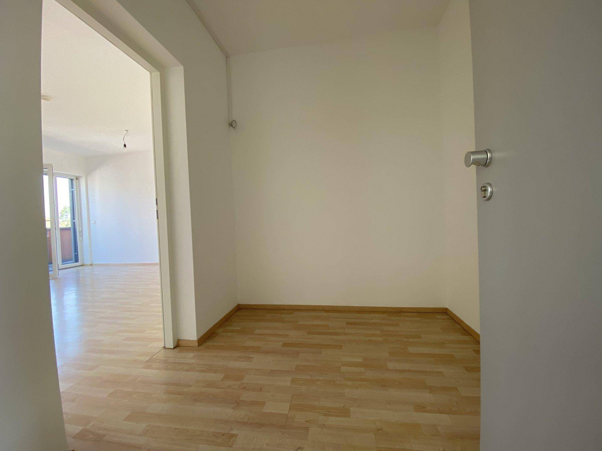 Heller Eingangsbereich mit hellem Laminatboden und weiß gestrichenen Wänden.