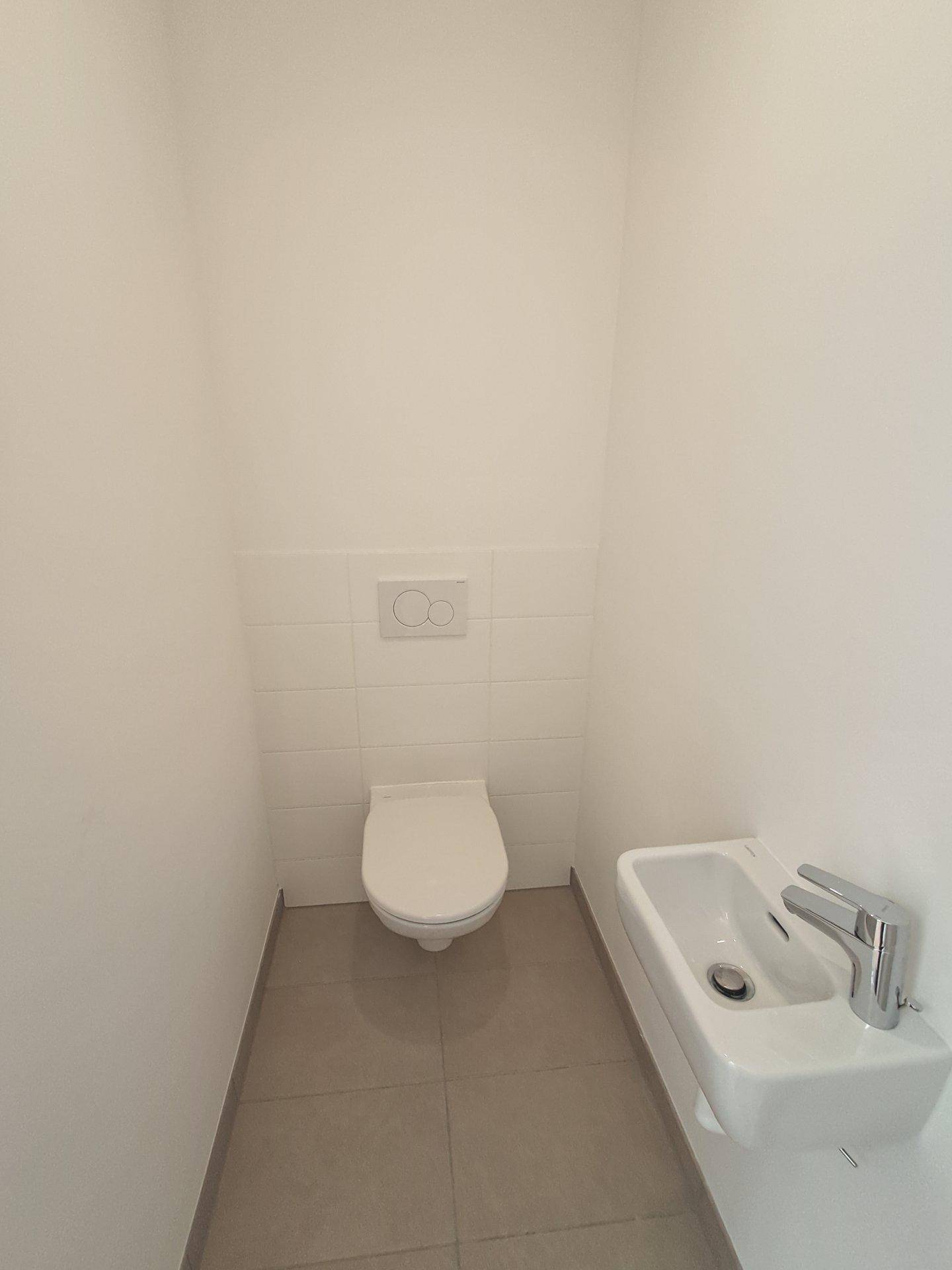 Modernes Gäste-WC mit wandhängendem WC und kleinem Waschbecken.