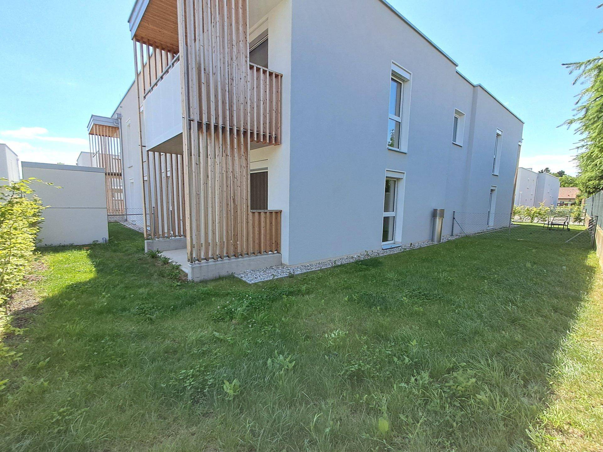 Ansicht eines modernen Neubaus mit schlichter Fassade und gepflegtem Rasenbereich.