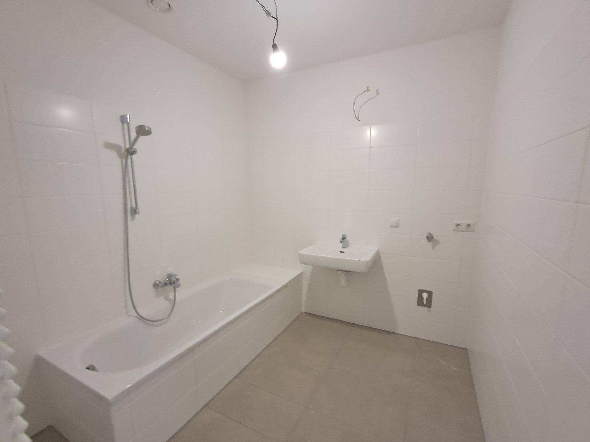 Modernes Badezimmer mit Badewanne, Waschbecken und weißen Fliesen.