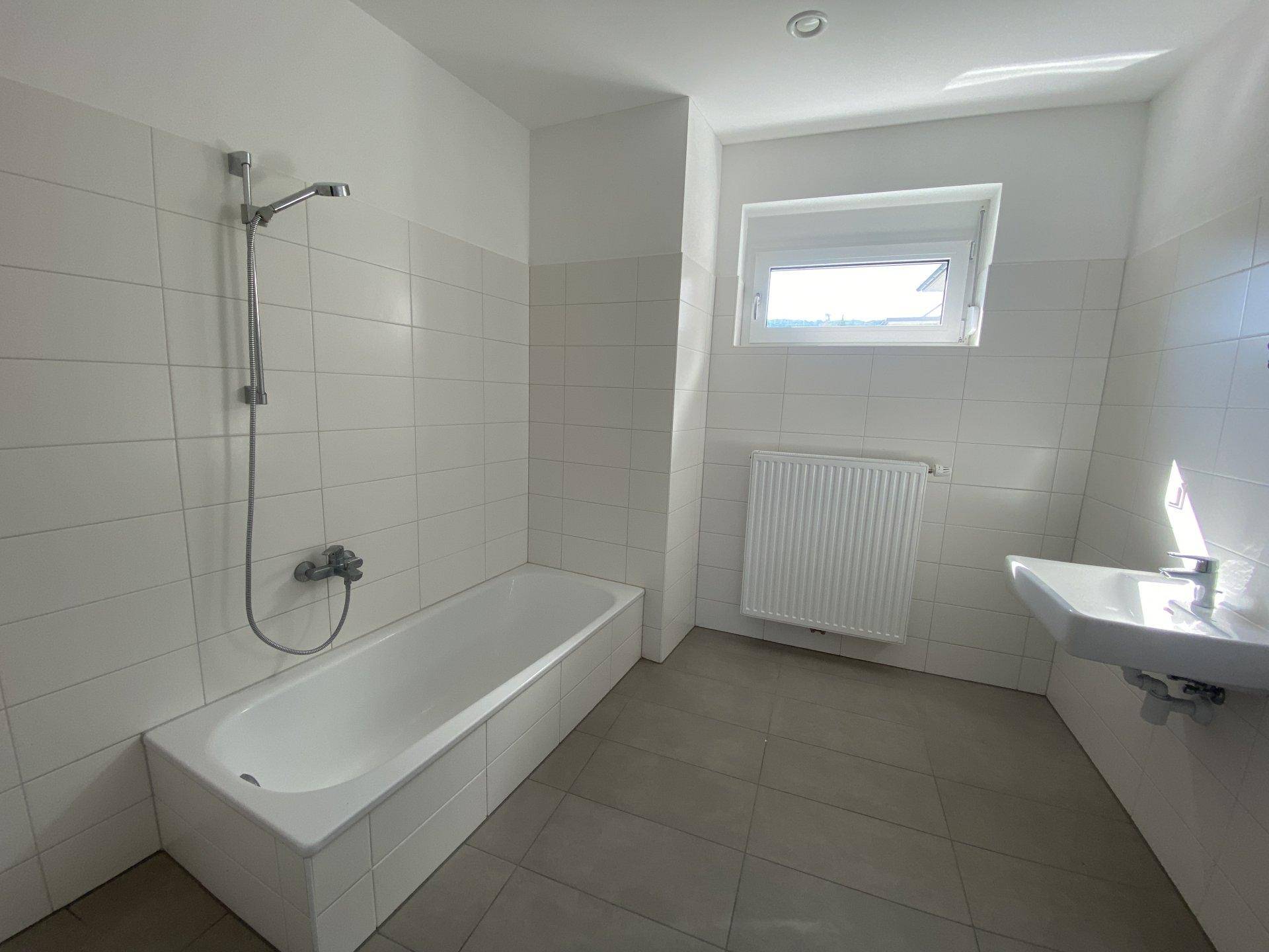 Modernes Badezimmer mit Badewanne, Dusche, Waschbecken und Fenster.
