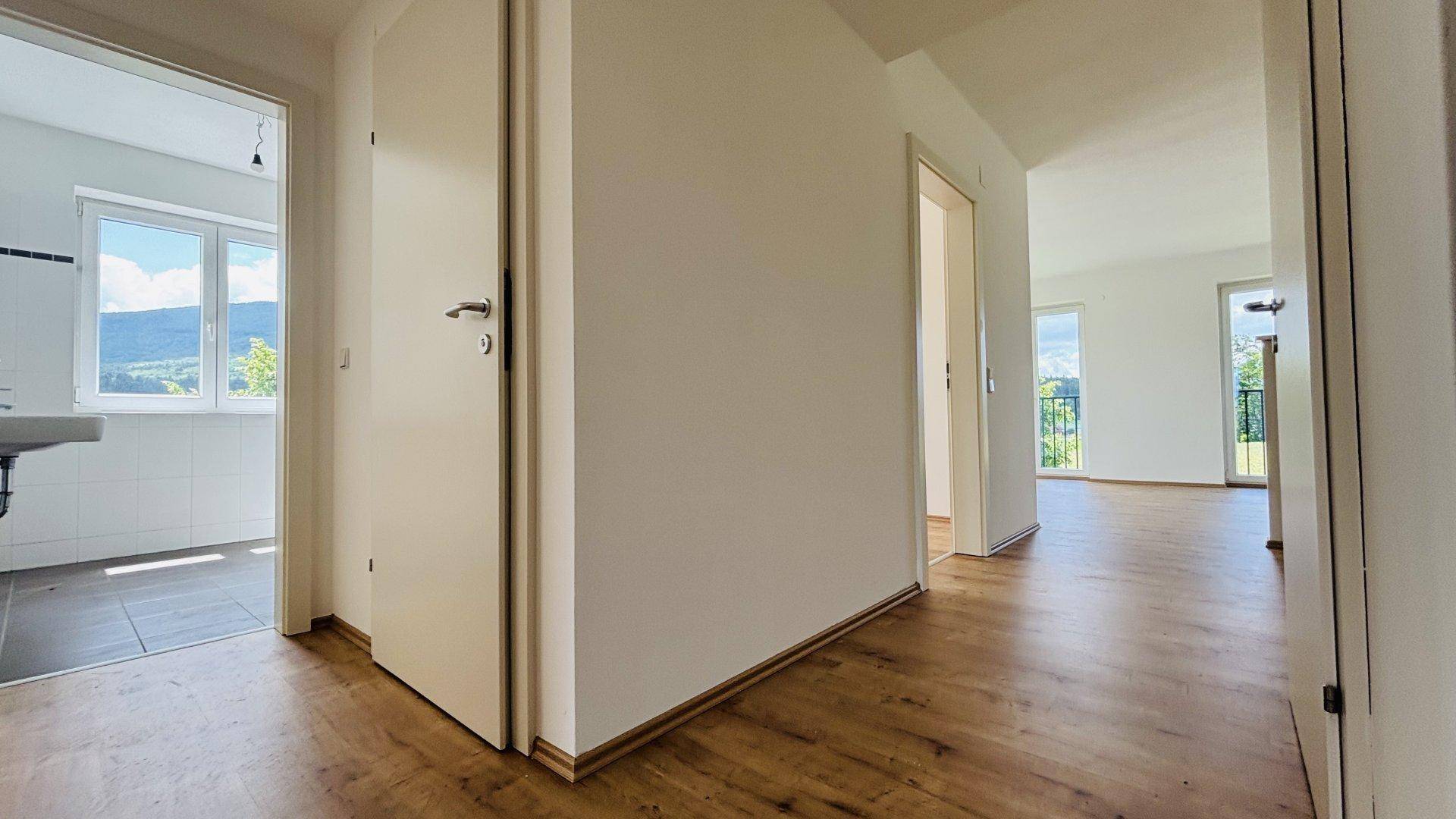 Heller Flur mit Laminatboden, der zu verschiedenen Zimmern und dem Badezimmer führt.