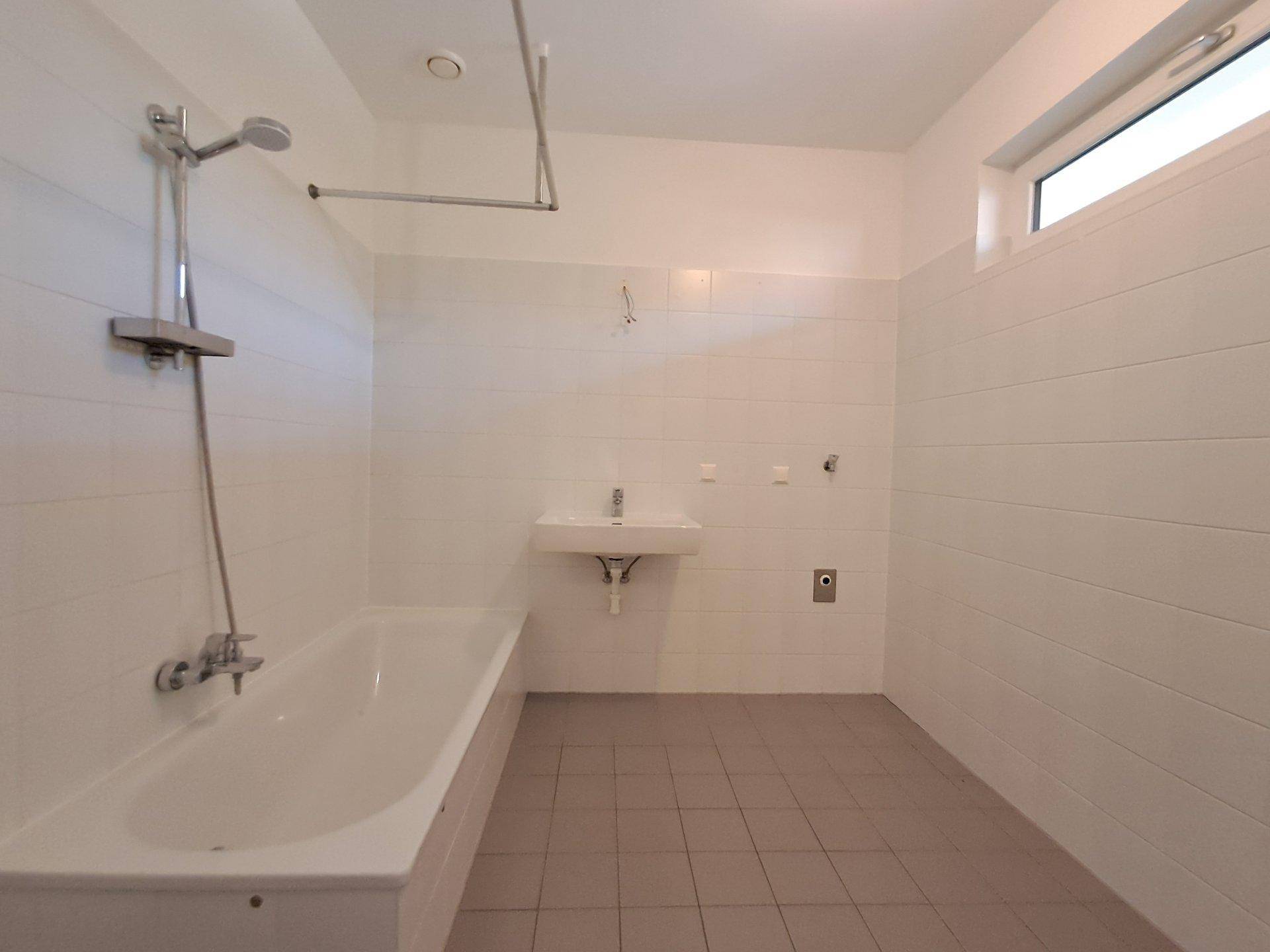 Modernes Badezimmer mit Badewanne, Dusche, Waschbecken und einem Fenster für Tageslicht.