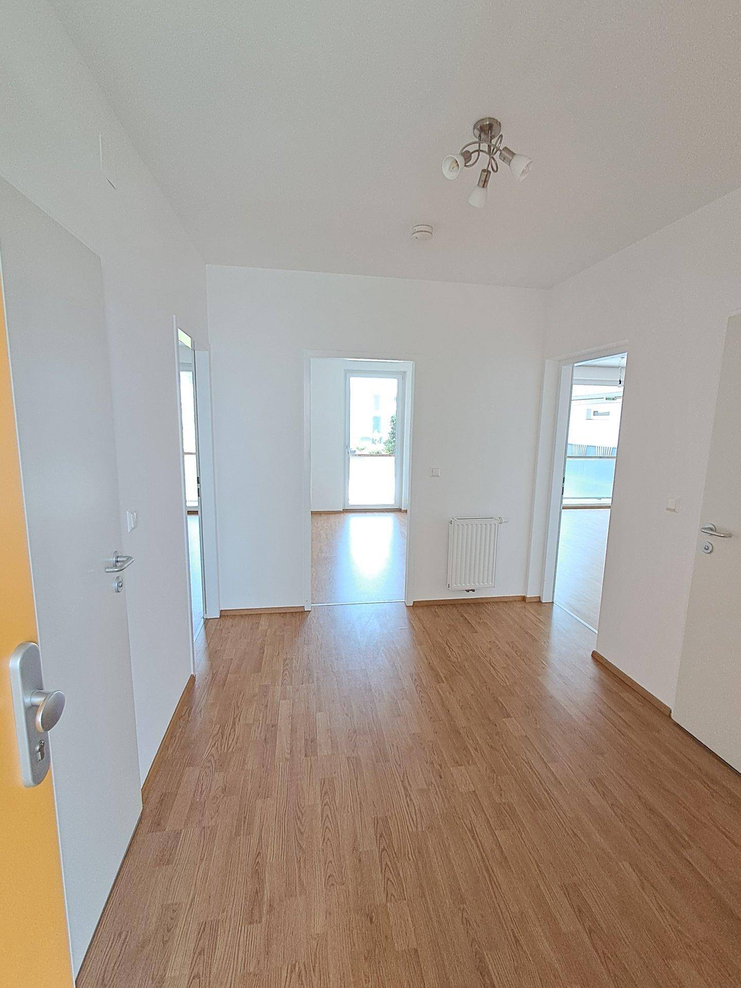 Heller Flur mit Laminatboden, der Zugang zu mehreren Zimmern der Wohnung bietet.