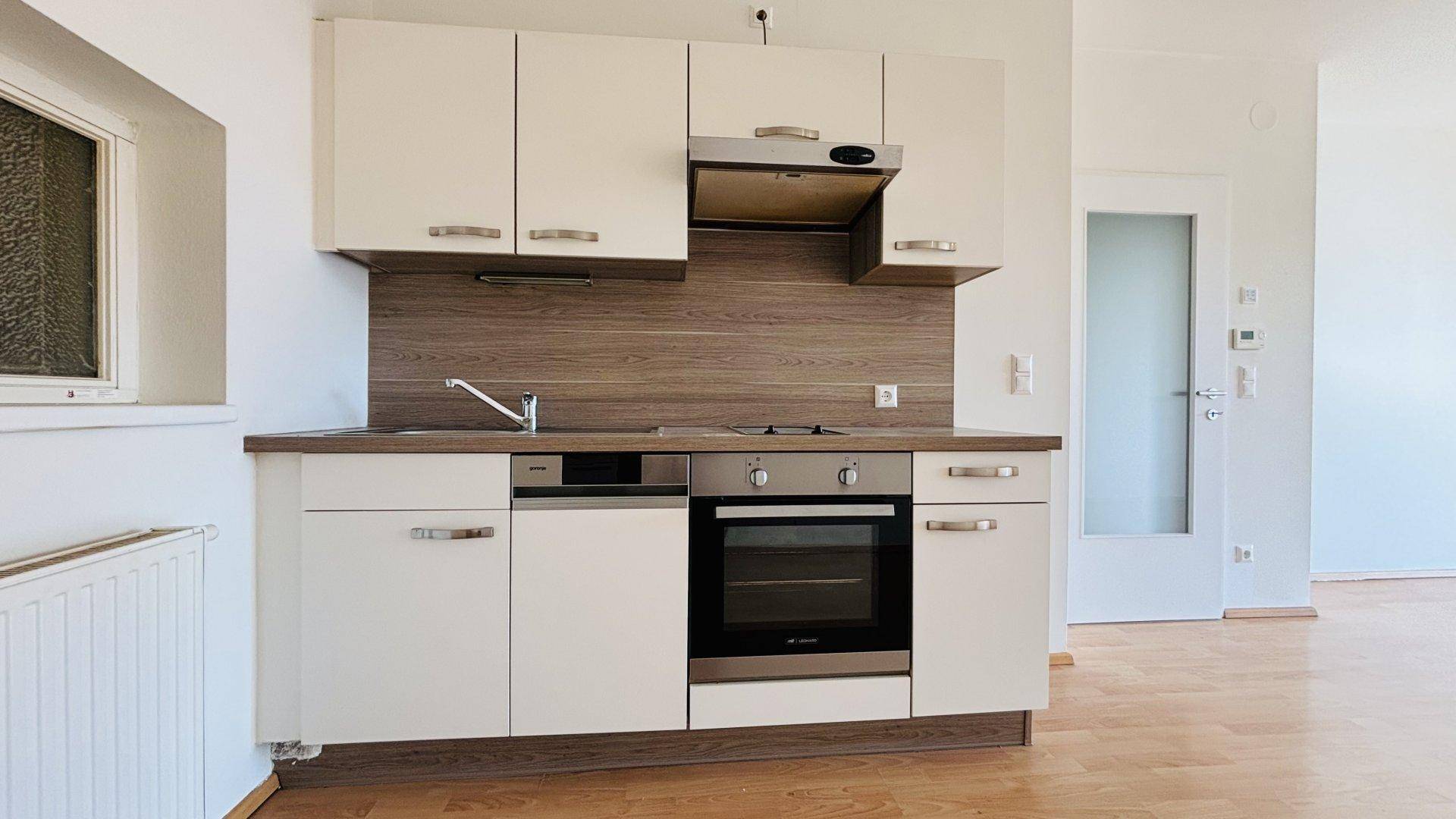 Moderne Küchenzeile mit Spüle, Kochfeld und Backofen, ideal für kleine Wohnungen.