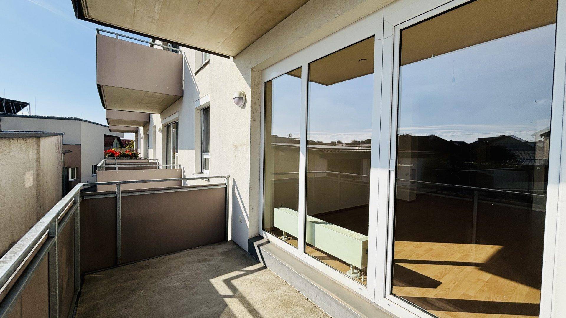 Geräumiger Balkon mit Metallgeländer und Blick auf die Umgebung, zugänglich vom Wohnbereich.