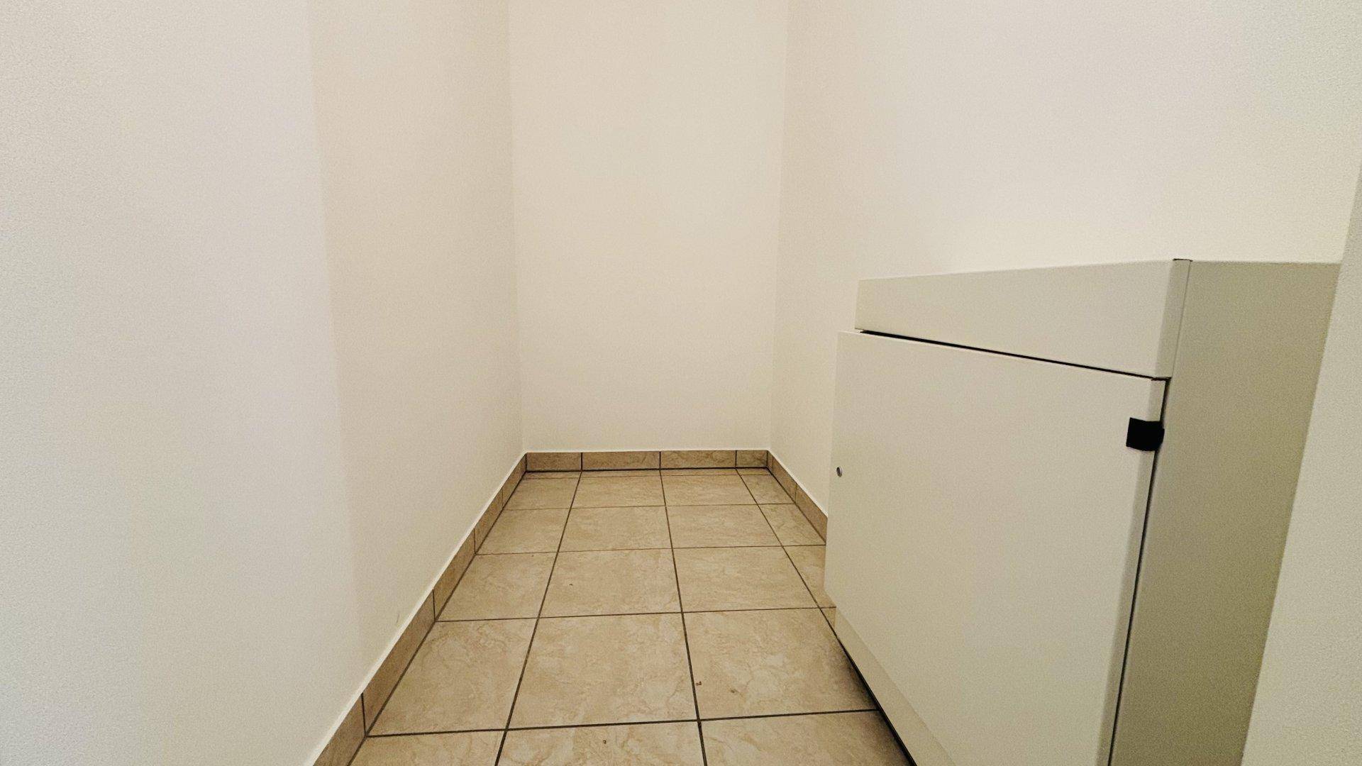 Kleiner Abstellraum mit Fliesenboden und einem Schrank, ideal für zusätzlichen Stauraum.