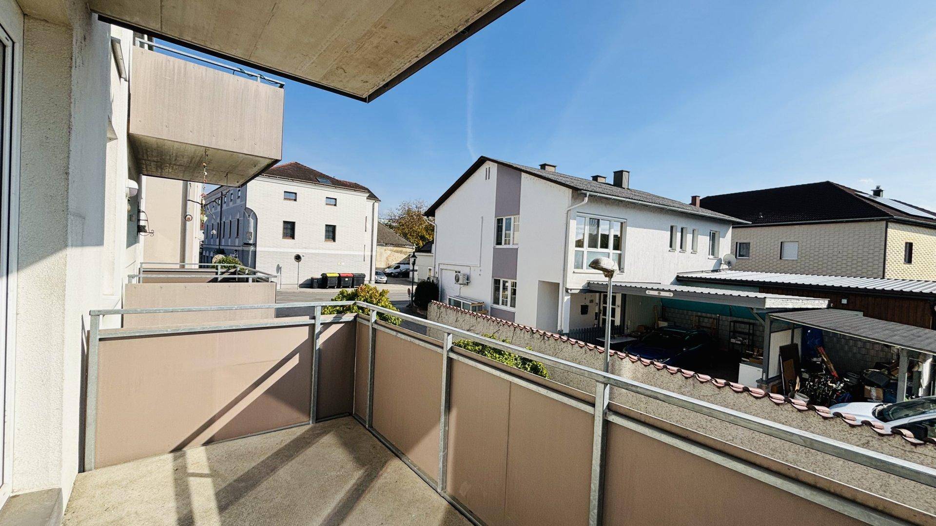 Balkon mit Blick auf die umliegenden Häuser und den blauen Himmel an einem sonnigen Tag.