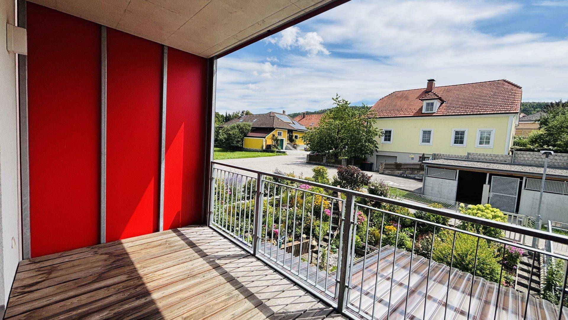 Geräumiger Balkon mit Holzboden und weitem Blick über den Garten und die Nachbarschaft.