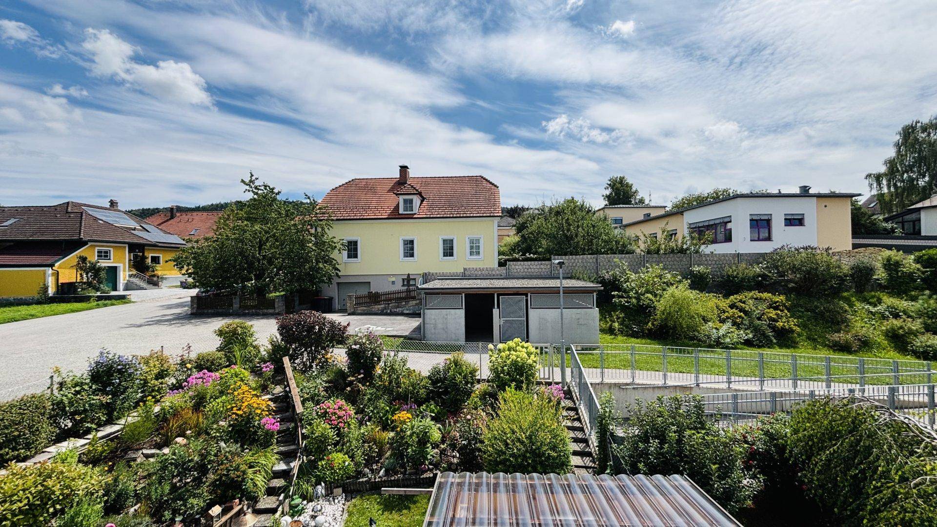 Gepflegter Gartenbereich mit vielfältigen Pflanzen und Blumen, umgeben von Wohnhäusern.