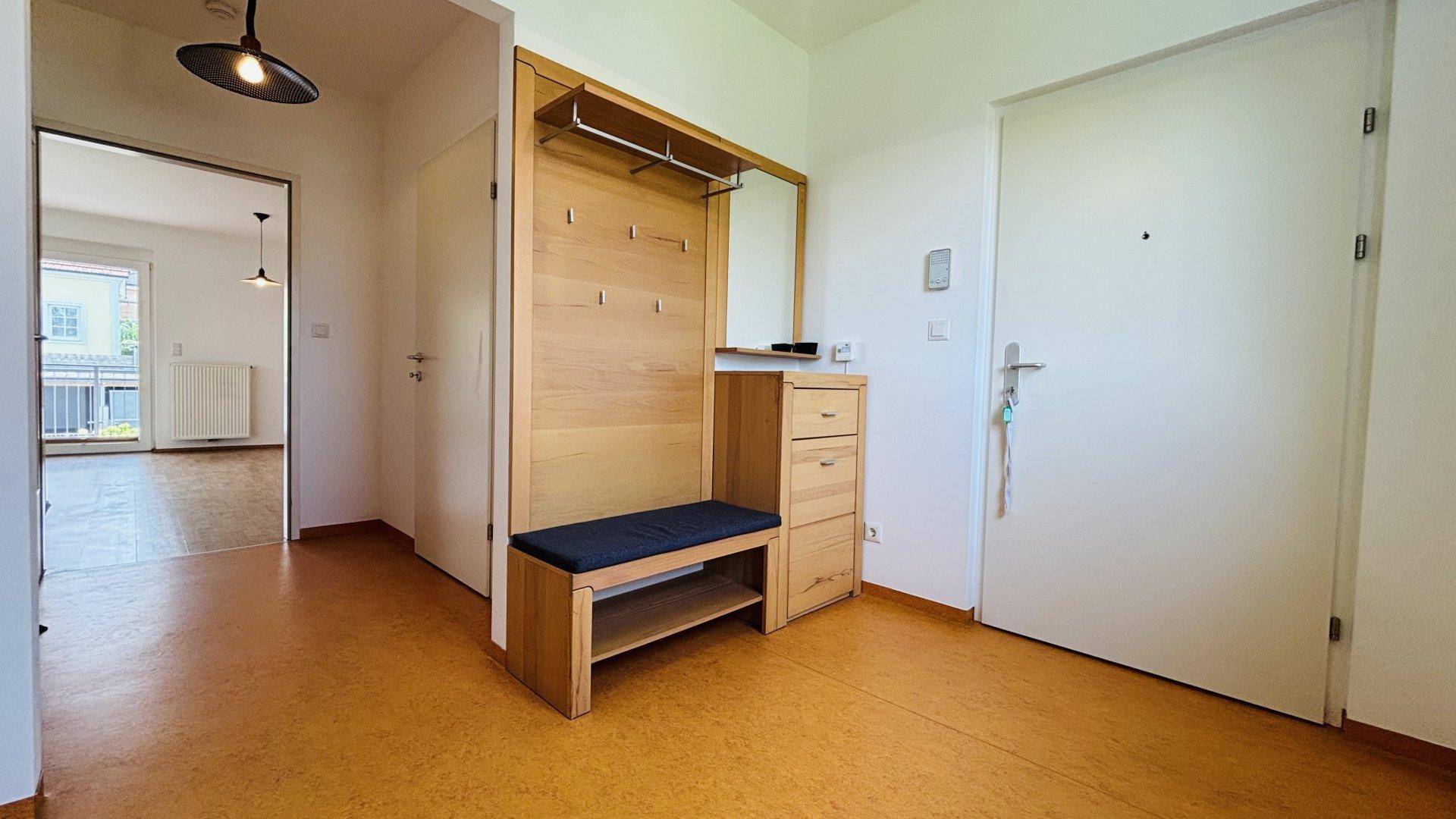 Eingangsbereich mit Garderobe, Sitzbank und hellem Laminatboden.