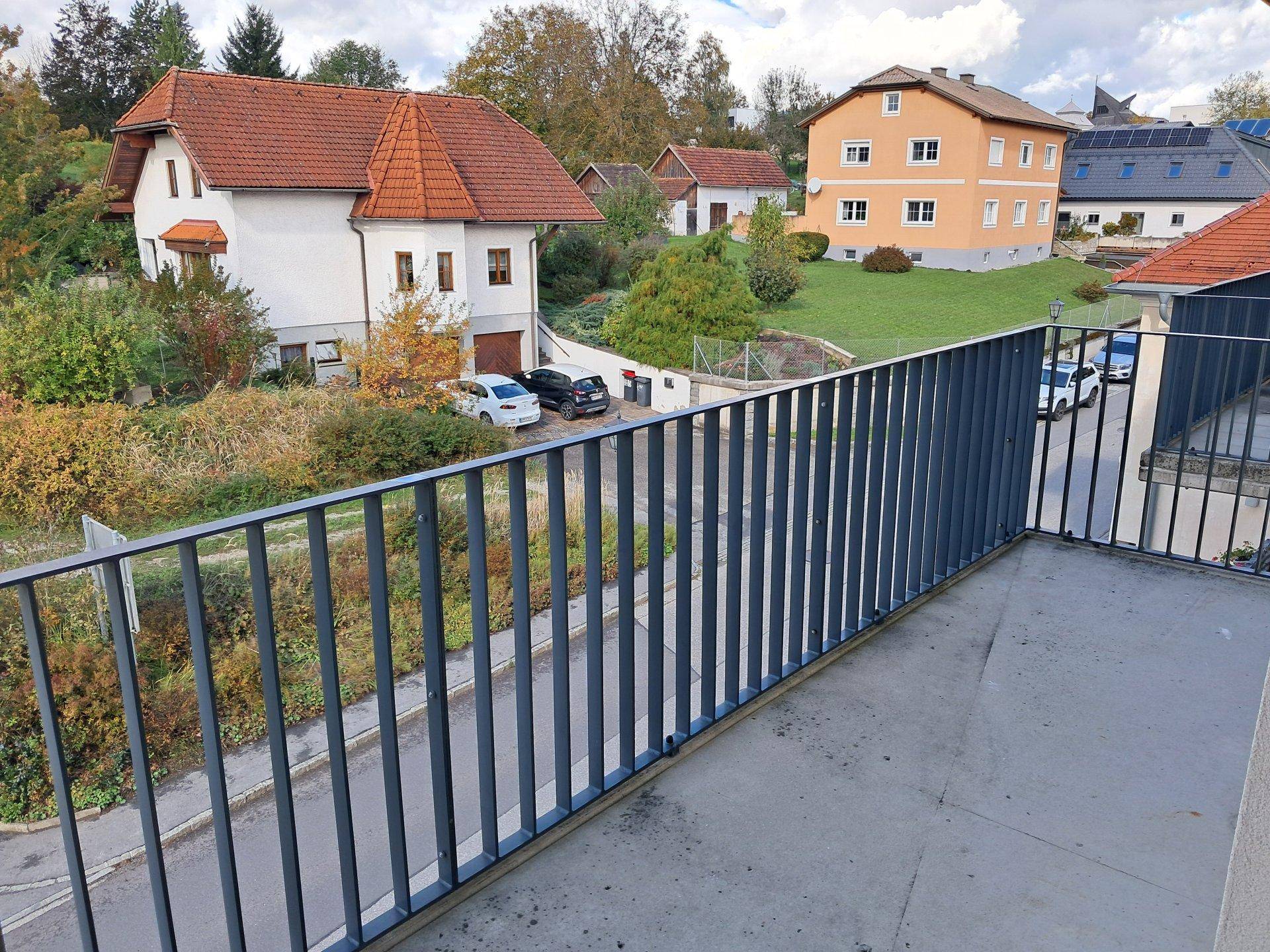 Blick von einem Balkon auf eine Wohnsiedlung mit Häusern und Gärten.