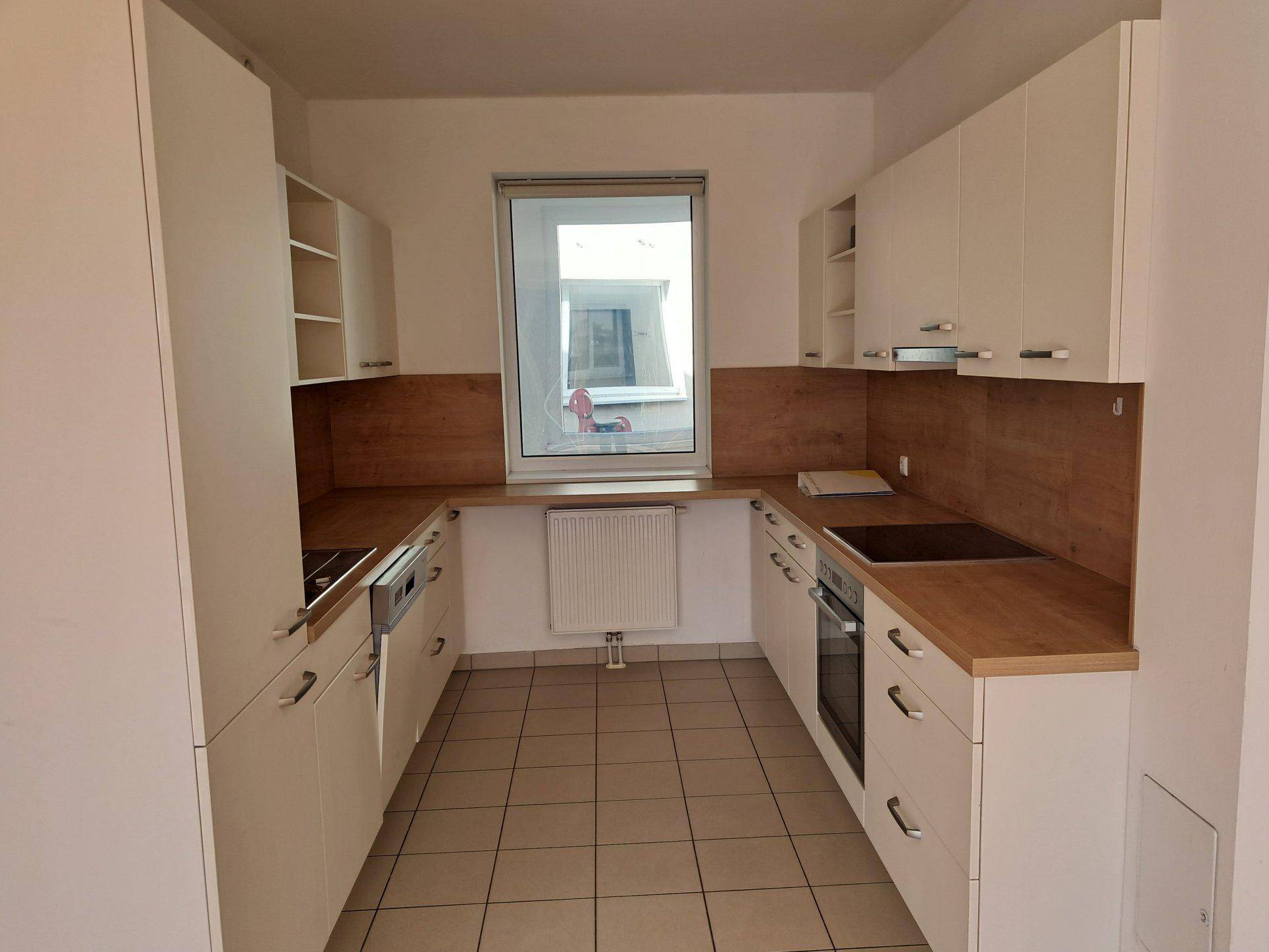 Helle Küche mit weißen Schränken, Holzoptik-Arbeitsplatten und Fliesenboden.