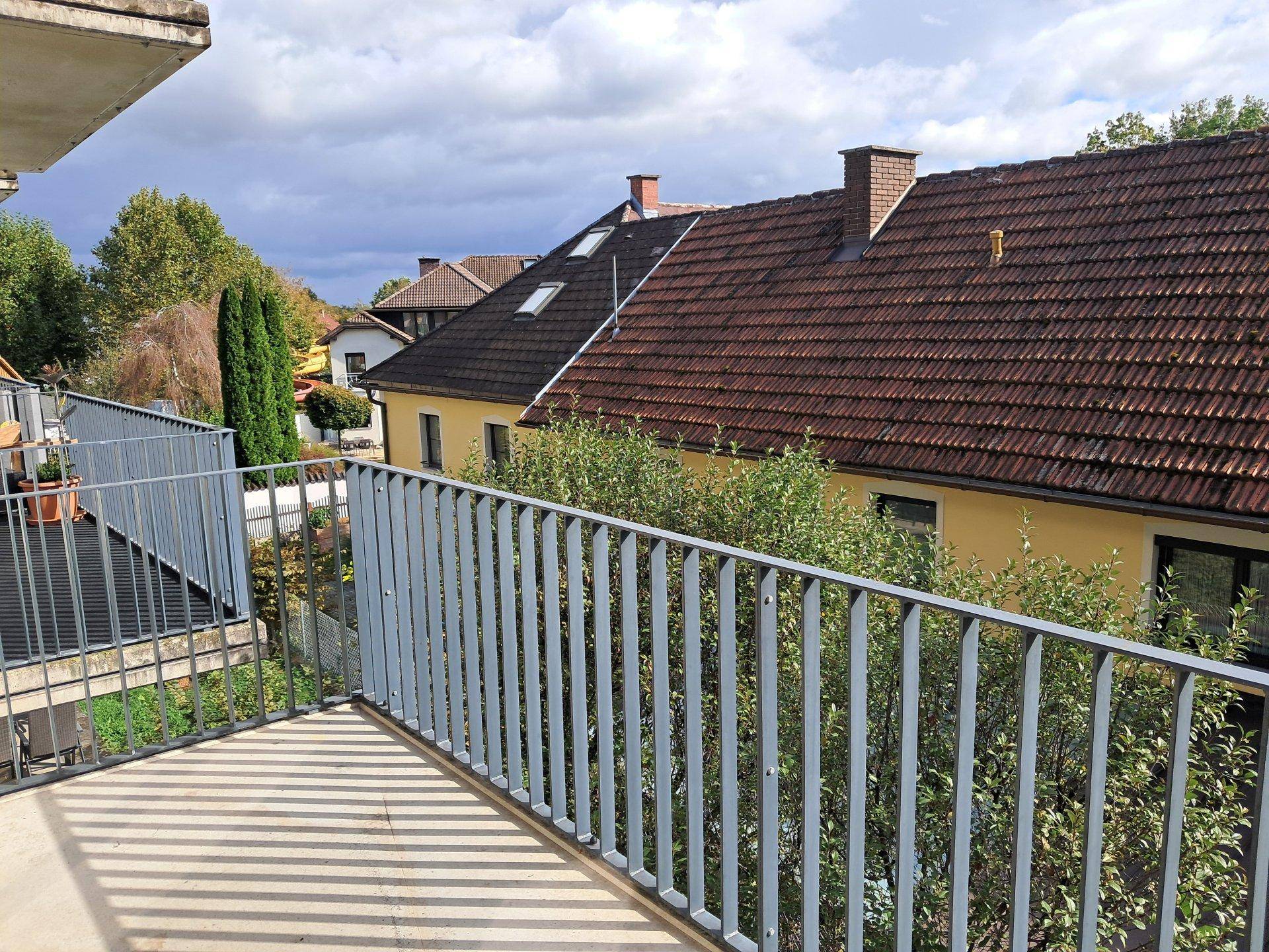 Balkon mit Metallgeländer und Blick auf die Dächer der Nachbargebäude.