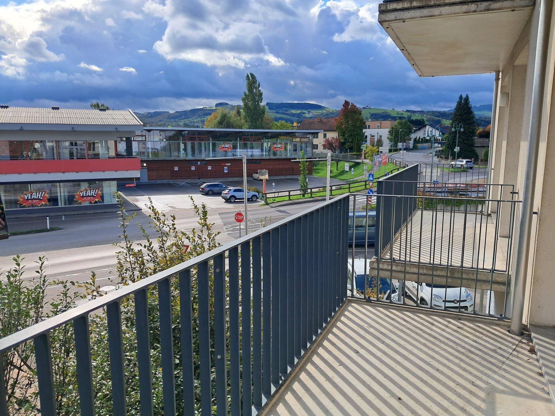 Balkon mit Metallgeländer und Blick auf die umliegende Stadt und Landschaft.