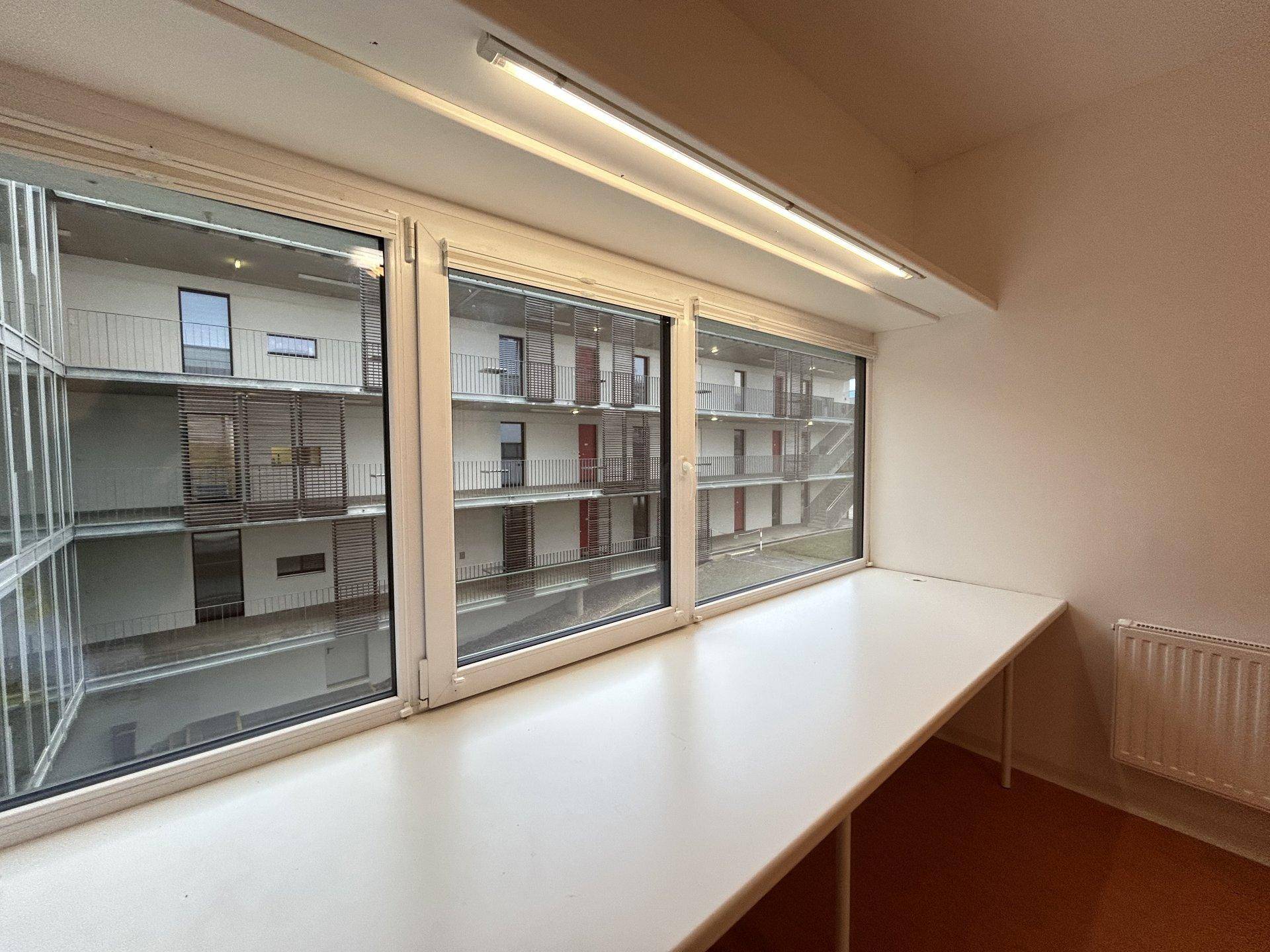 Große Fensterfront mit breiter Ablagefläche und Blick auf den gegenüberliegenden Gebäudeteil.