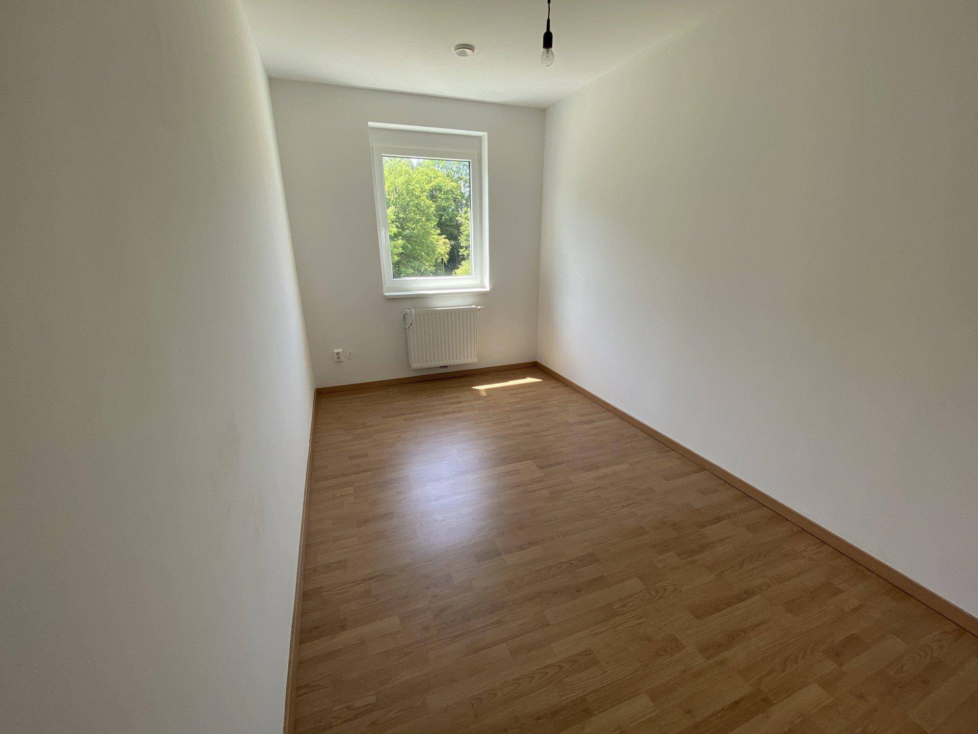 Unmöbliertes Schlafzimmer mit Holzboden und Fenster, bietet eine helle und ruhige Atmosphäre.