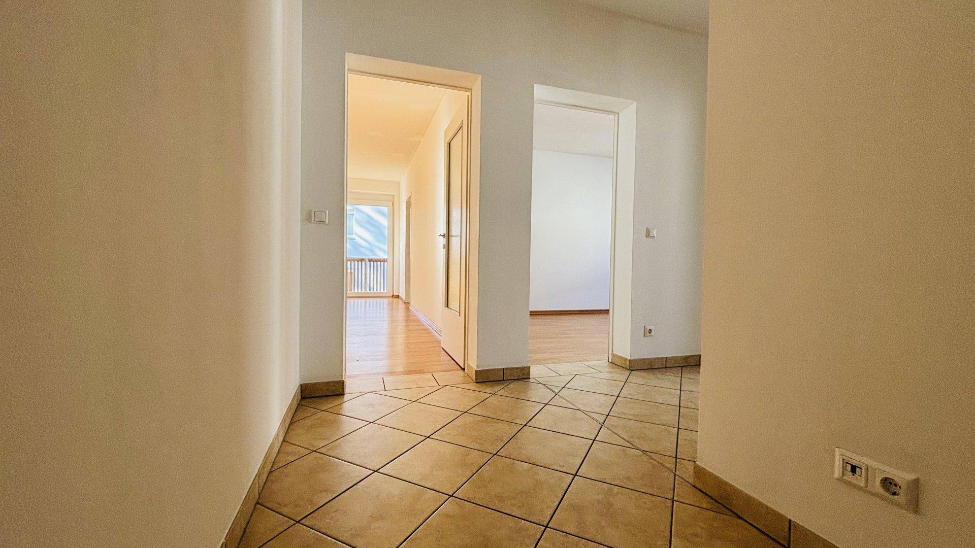 Heller Flur mit beigefarbenen Fliesen und Zugang zu verschiedenen Räumen der Wohnung.