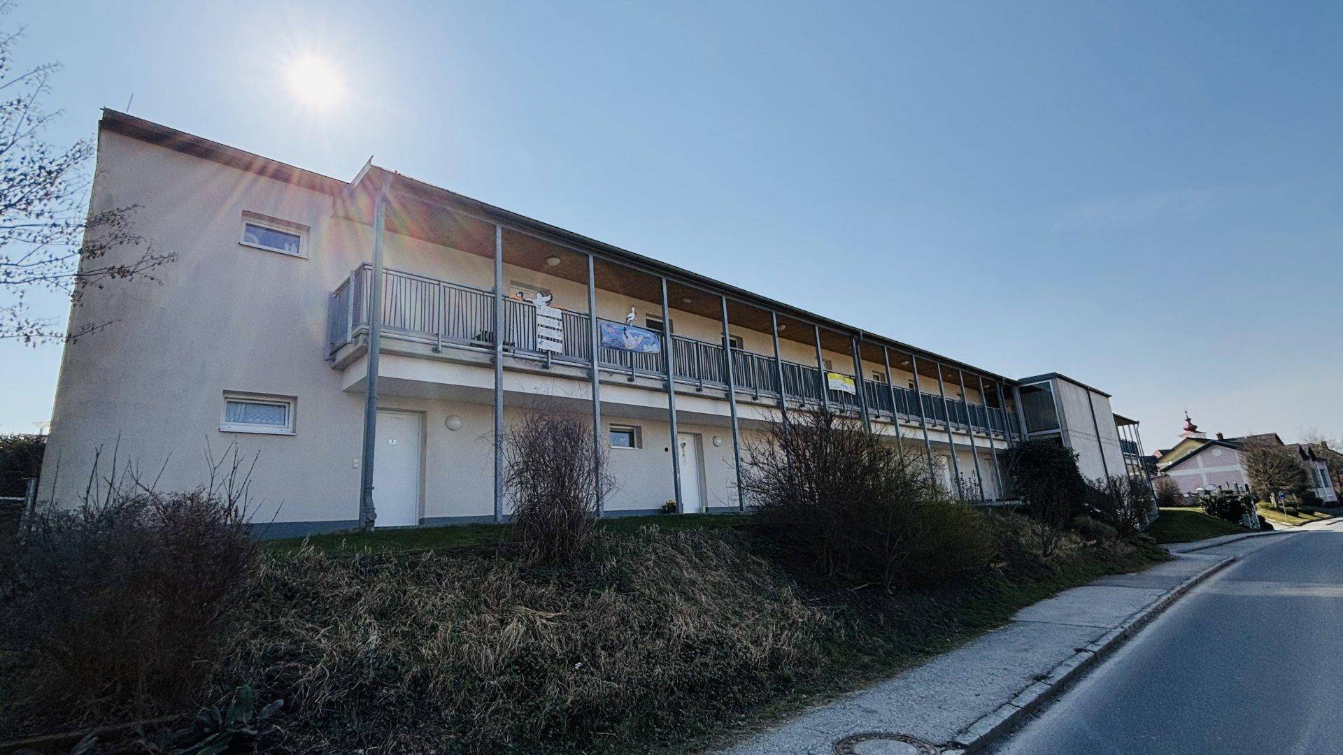 Längsseite eines modernen Wohngebäudes mit vielen überdachten Balkonen und sonniger Ausrichtung.