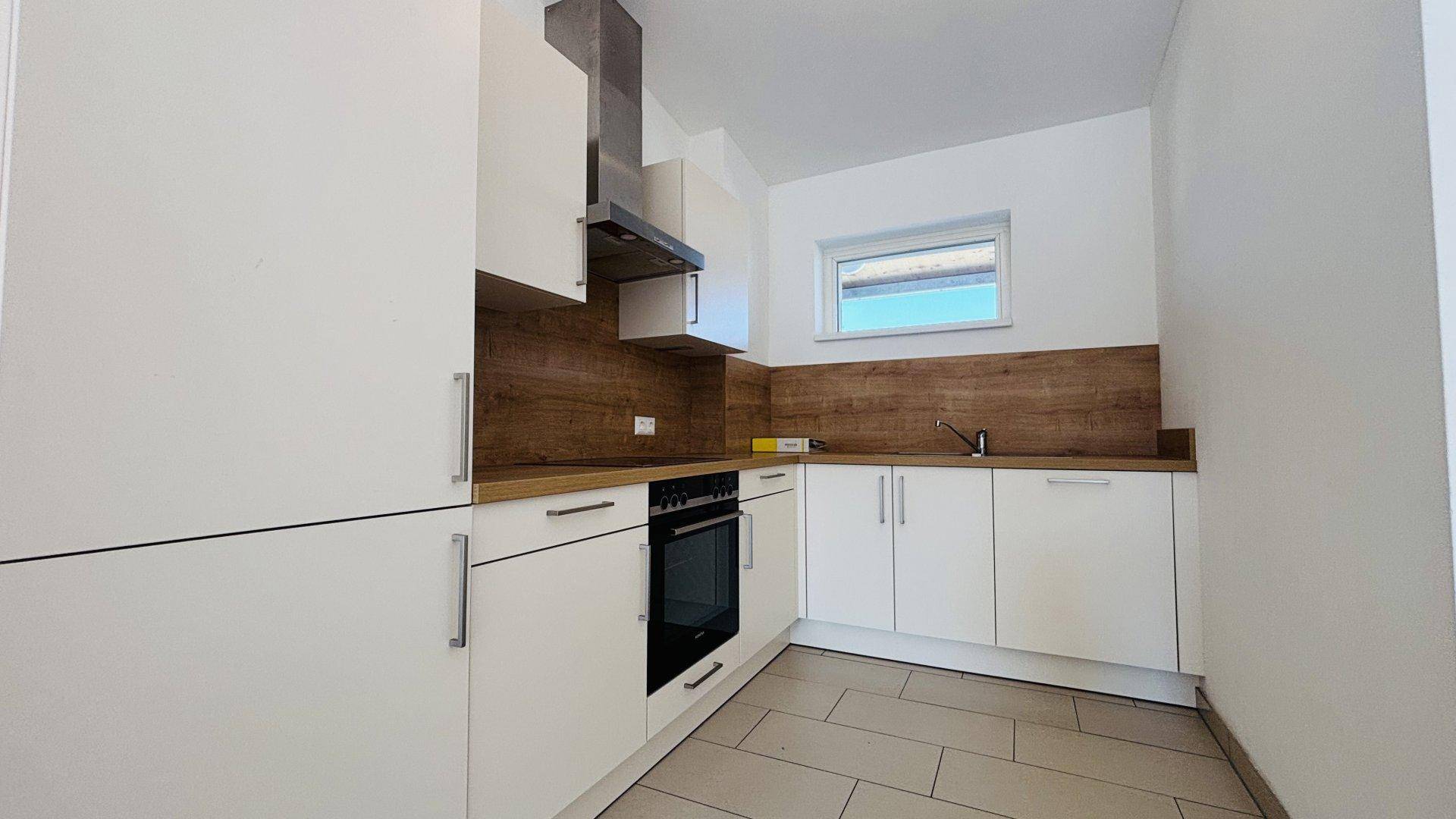 Moderne Einbauküche mit weißen Schränken, Holzoptik-Arbeitsplatte und Dunstabzugshaube.
