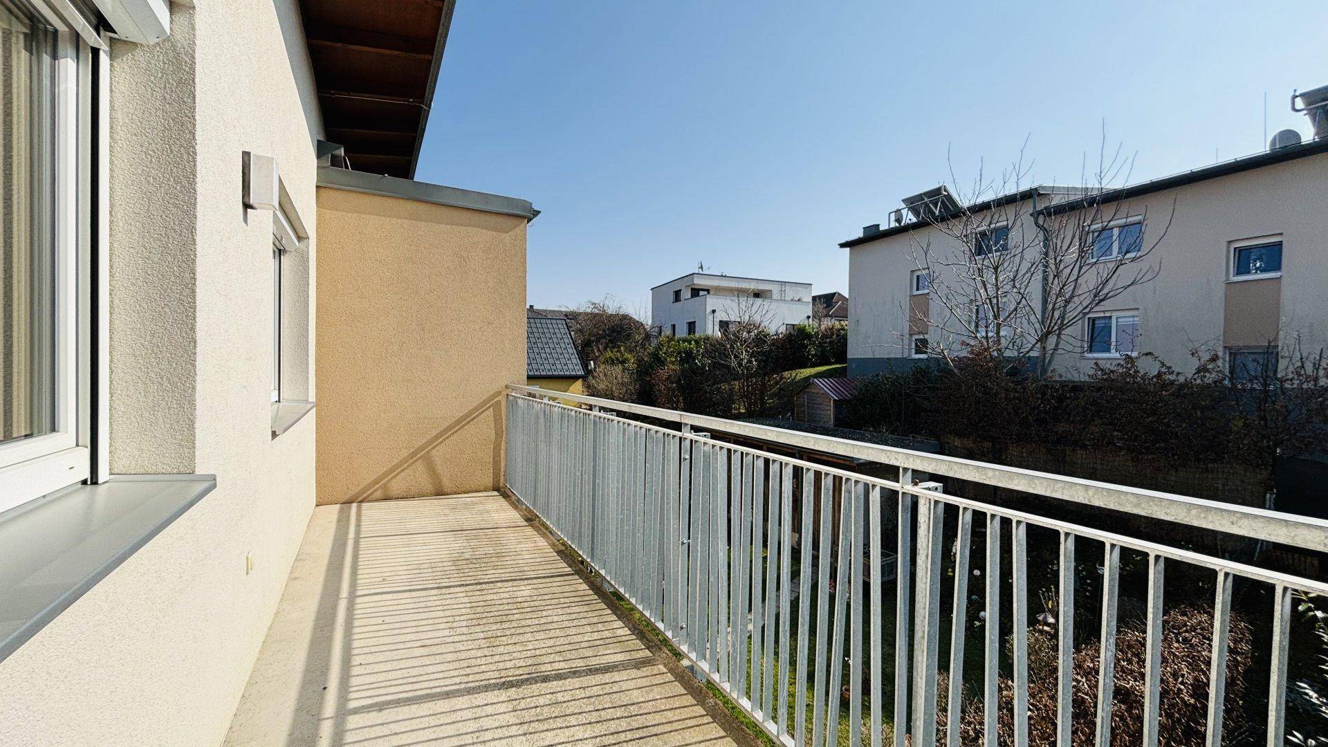 Heller Balkon mit Metallgeländer und Blick auf die umliegenden Gebäude und Gärten.