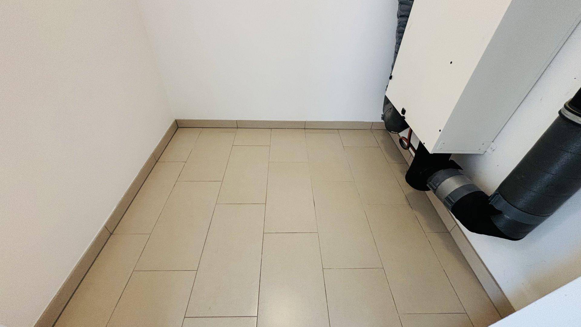 Kleiner Abstellraum oder Technikraum mit Fliesenboden und sichtbaren Installationen.