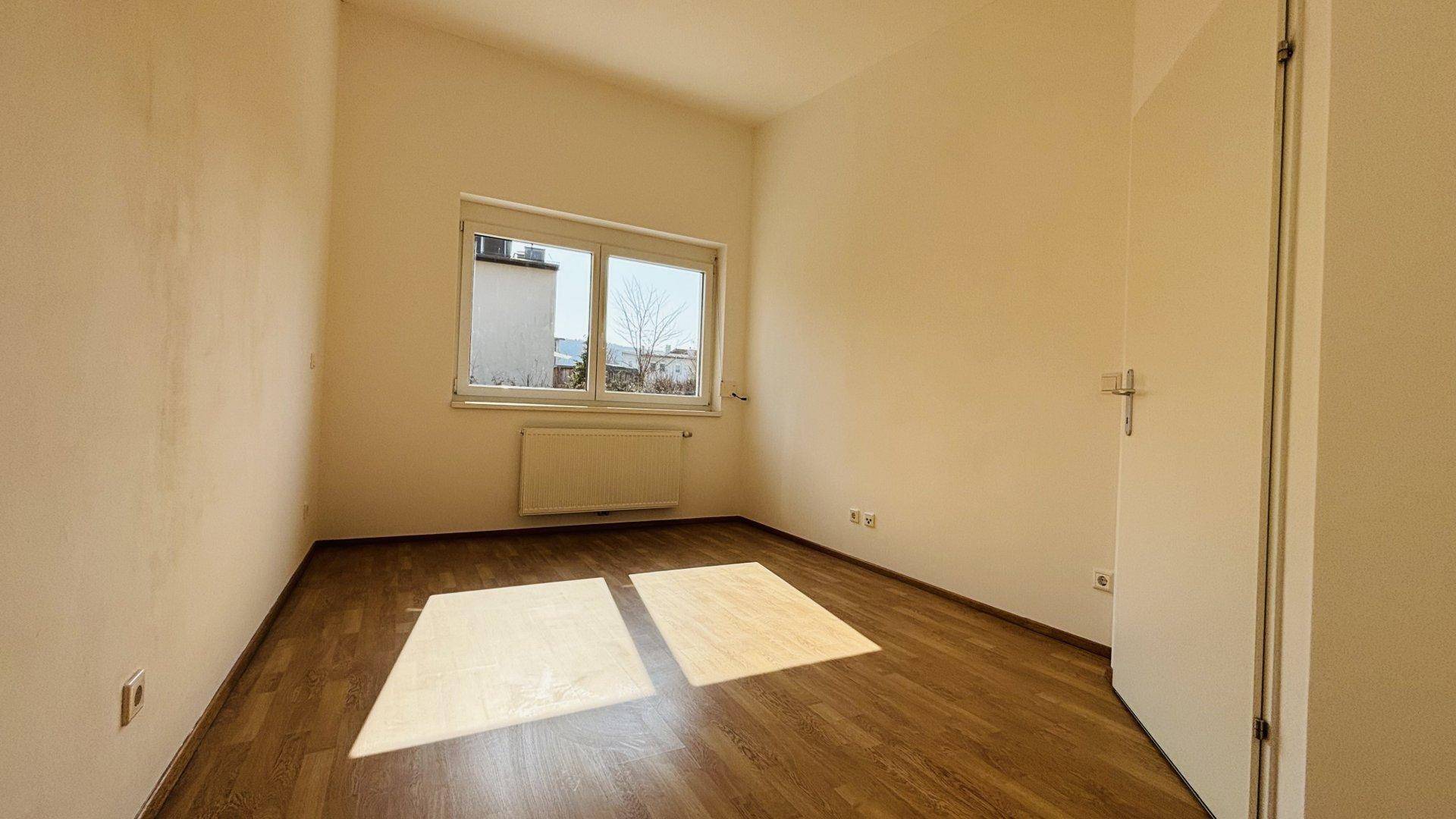 Geräumiges Schlafzimmer mit Laminatboden und einem Fenster, das den Raum gut belichtet.