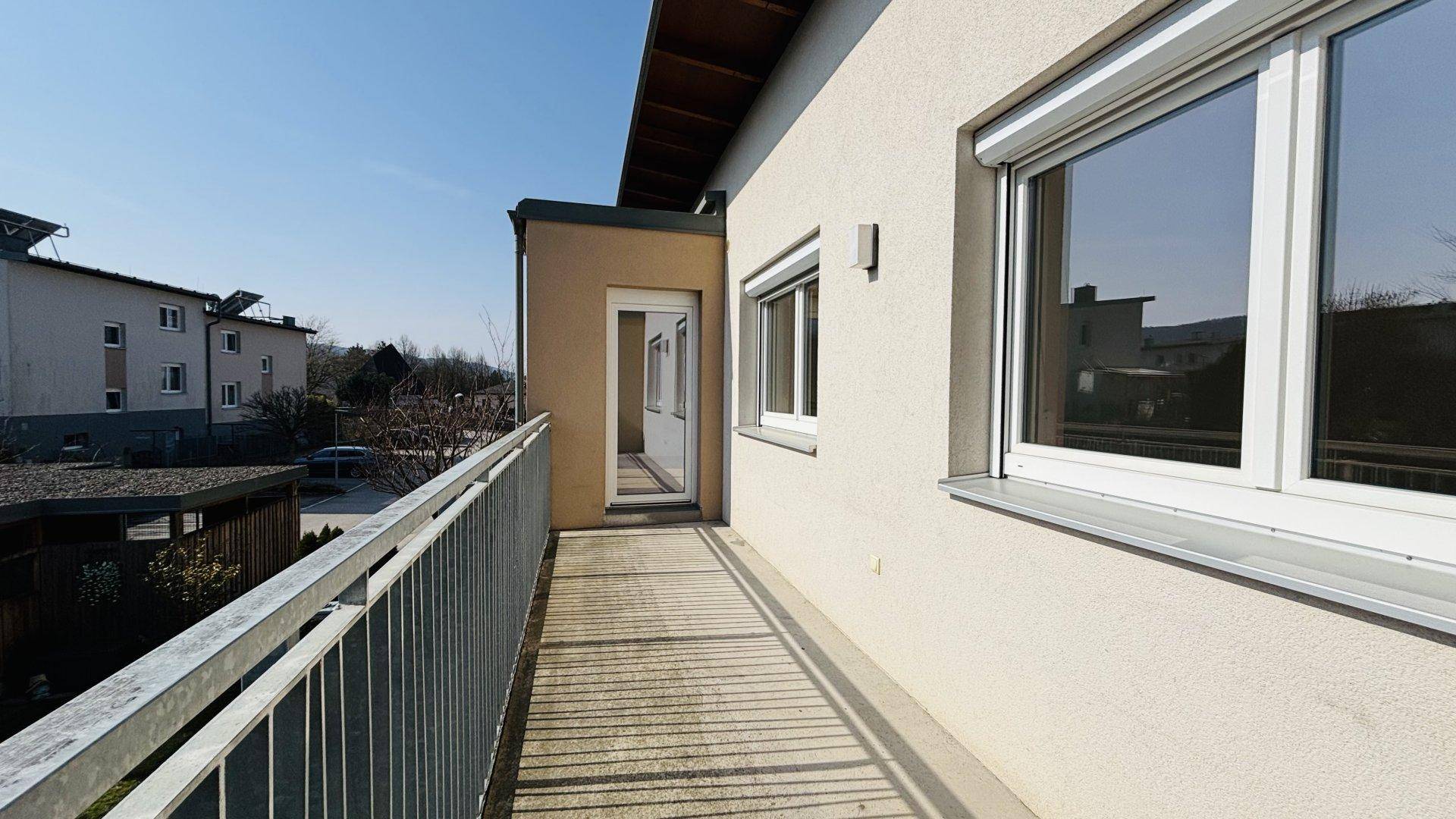 Schmaler Balkon mit Metallgeländer und Zugang zu einem Innenraum des Gebäudes.