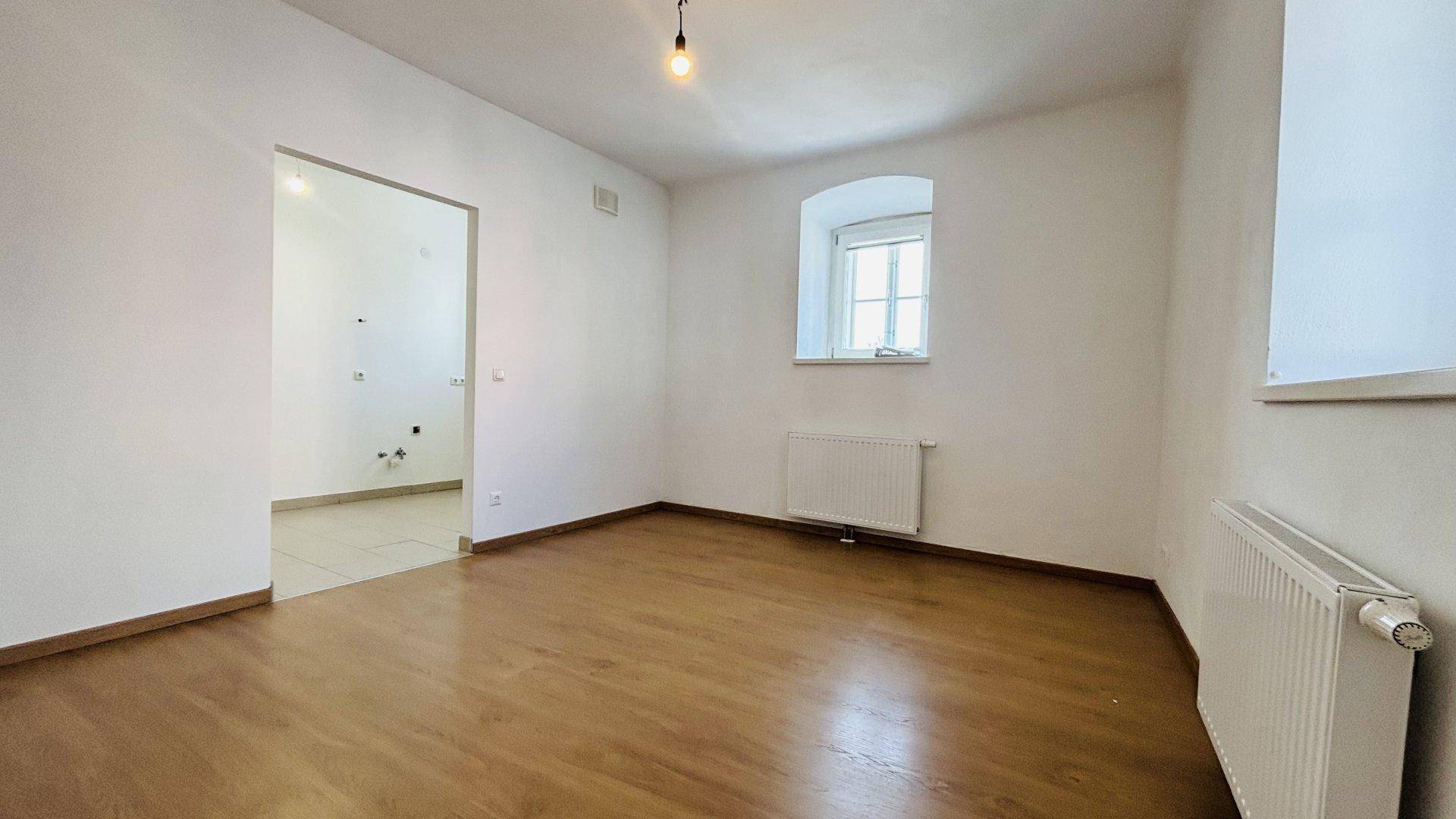 Helles Schlafzimmer mit Holzboden und weiß gestrichenen Wänden, bereit zur individuellen Gestaltung.