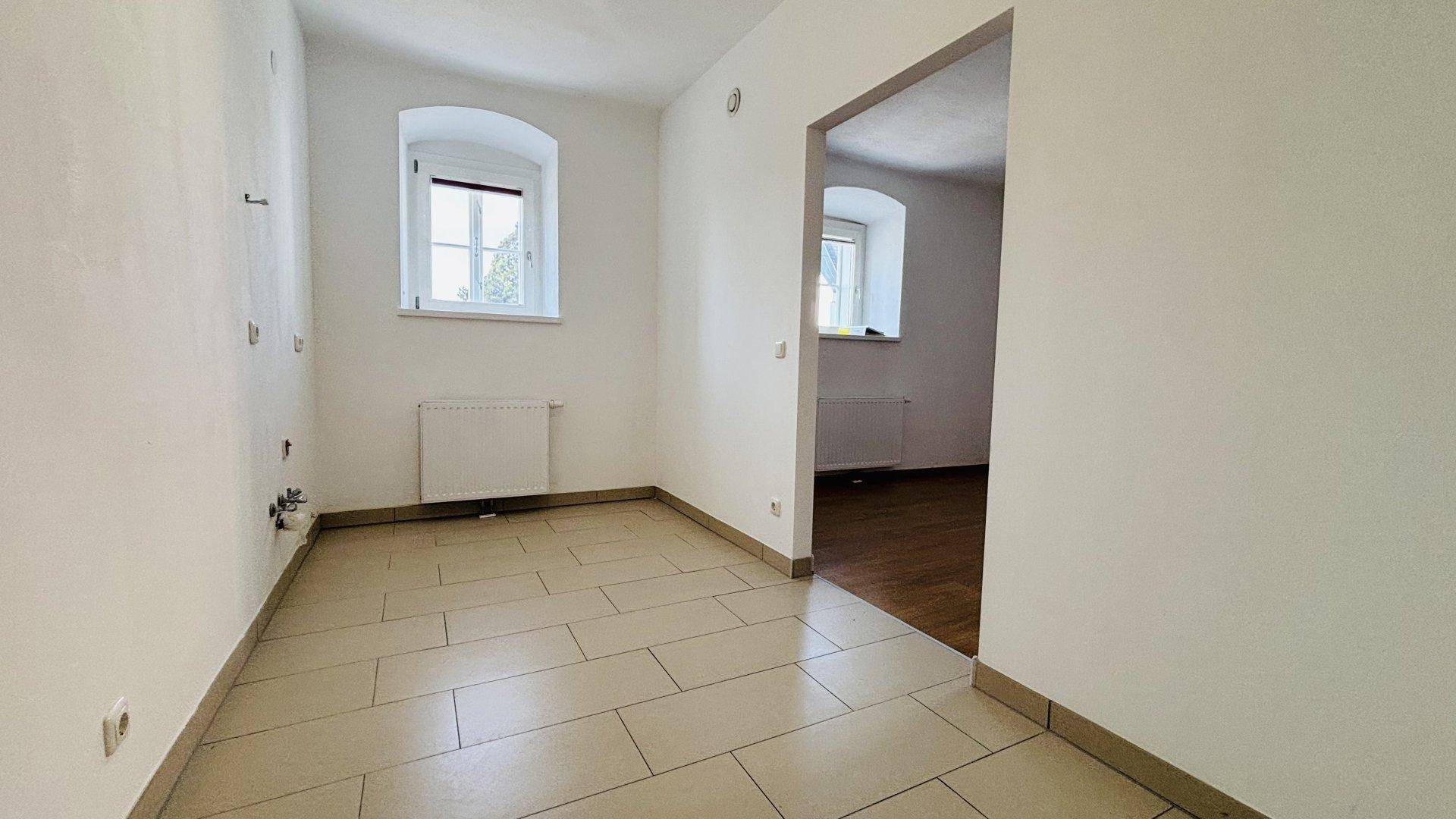 Raum mit Fliesenboden und Anschlüssen für eine Küche, bietet Potenzial für individuelle Gestaltung.