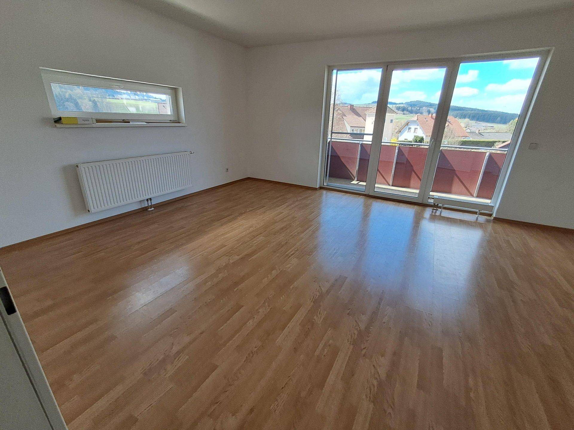 Geräumiger, heller Raum mit Holzboden und großen Fenstern, die viel Tageslicht hereinlassen.